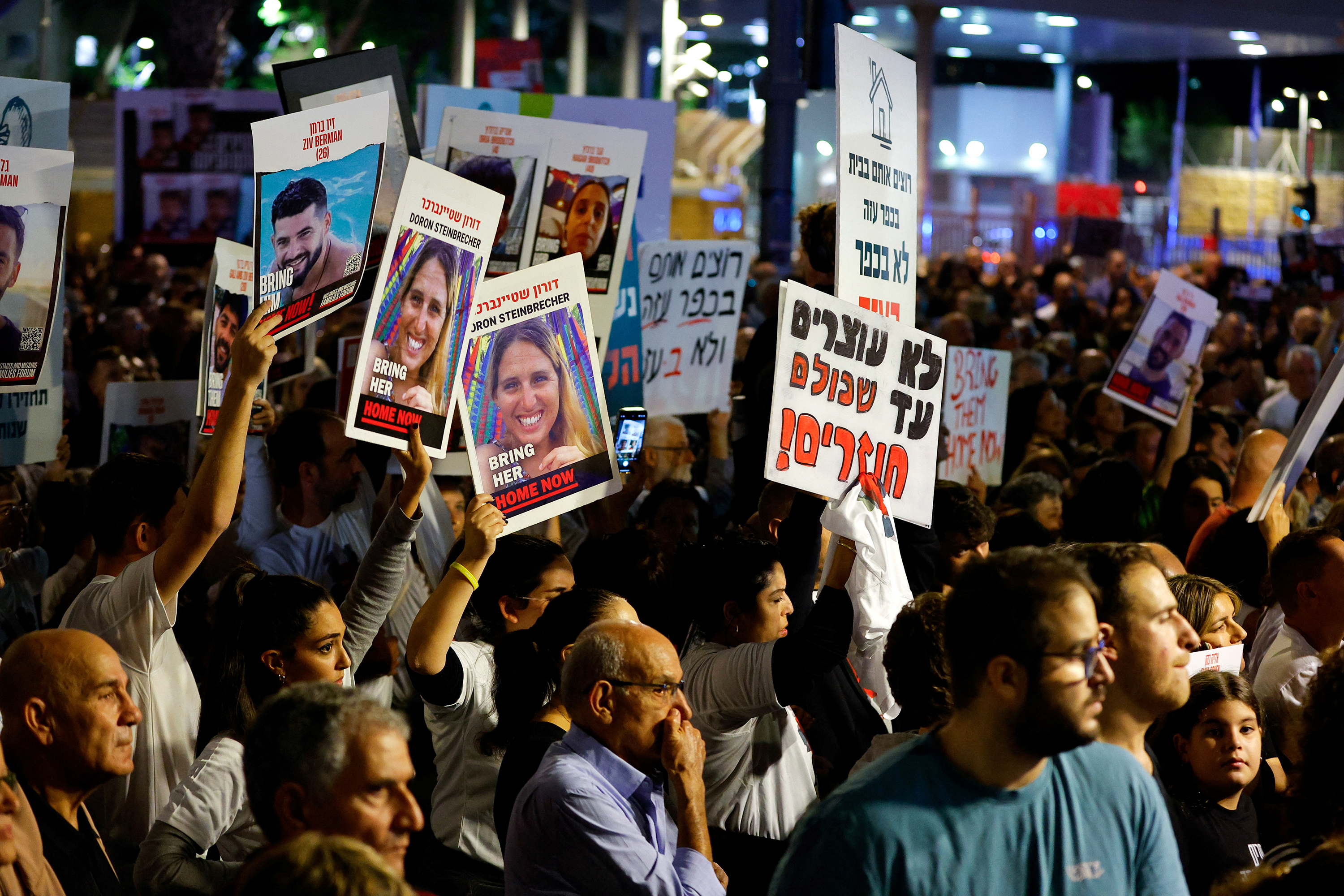 Oamenii țin pancarte în timp ce așteaptă vești despre ostaticii ținuți de Hamas pe 25 noiembrie, la Tel Aviv, Israel.