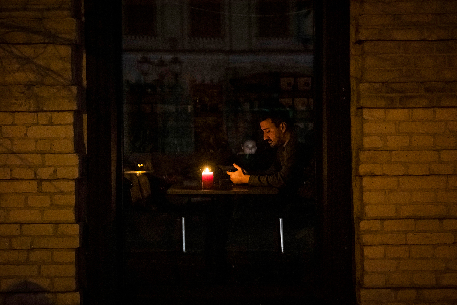 A man sits at a table of a restaurant with a candle in Kyiv on November 02.