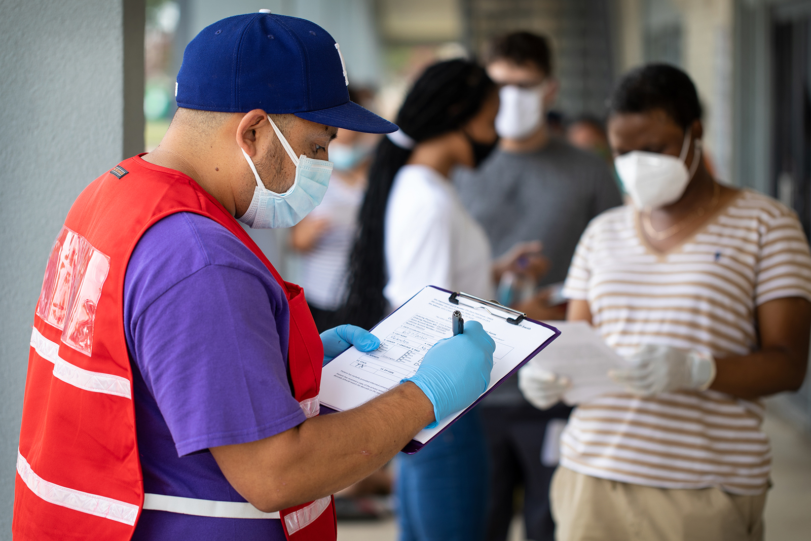 Community outreach specialist Rogelio Bucio collects patient information as they wait in line at a walk up Covid-19 testing site on June 27, in Dallas, Texas. 