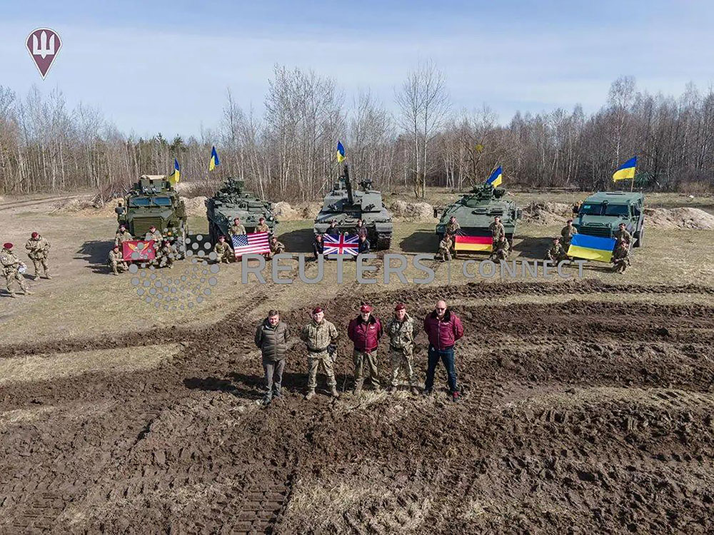 Ukraine's Defence Minister Oleksii Reznikov and Commander of the Air Assault Forces Maksym Myrhorodskyi pose for a picture in front of British Challenged 2 main battle tank, US Stryker and Cougar armoured personnel carriers and German Marder infantry fighting vehicle in an unknown location in Ukraine, in this handout picture released Monday, March 27.