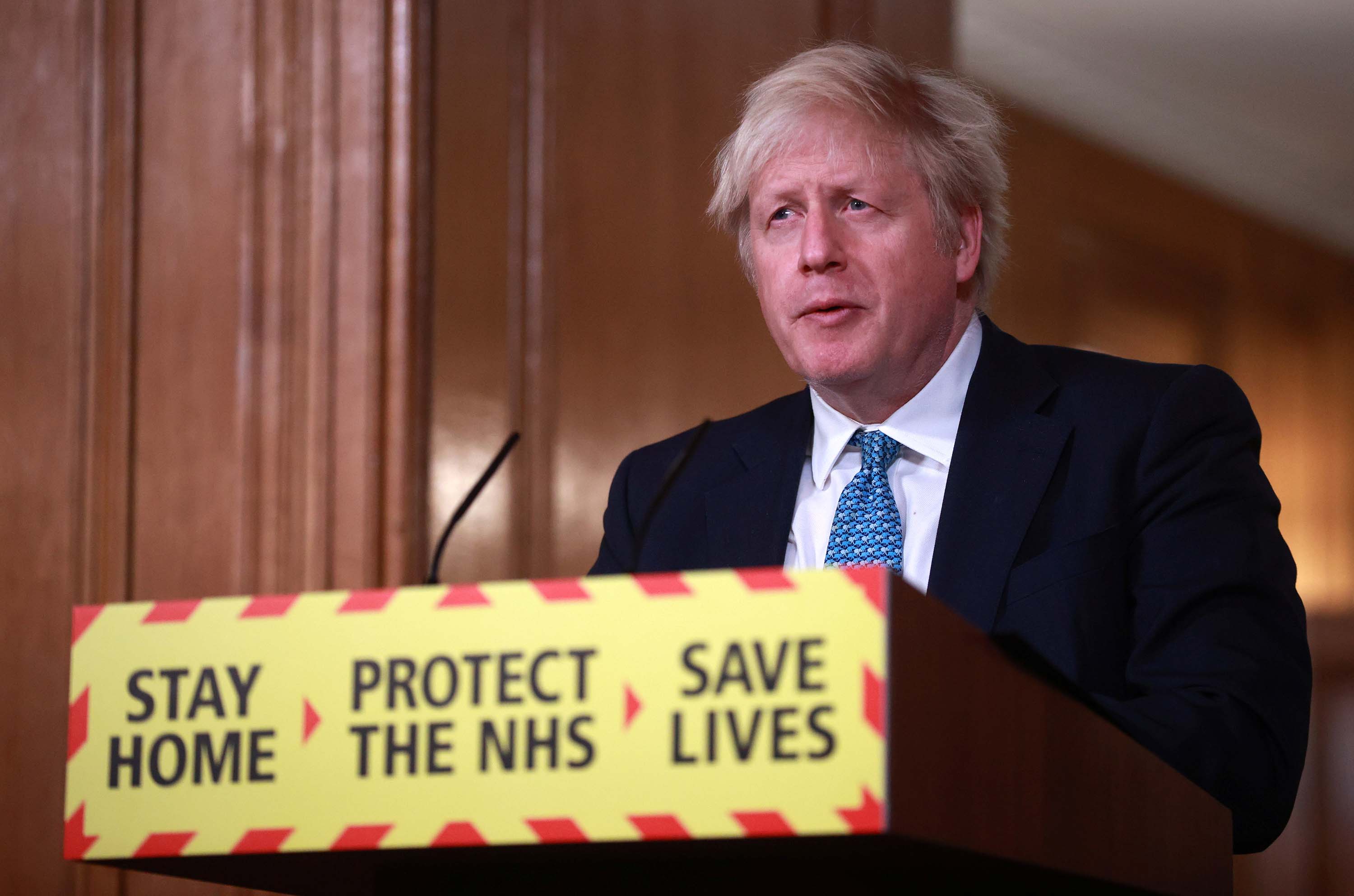 Britain's Prime Minister, Boris Johnson, attends a news conference with signage displaying the government slogan, "Stay Home, Protect the NHS, Save Lives," at 10 Downing Street in London, on January 5.