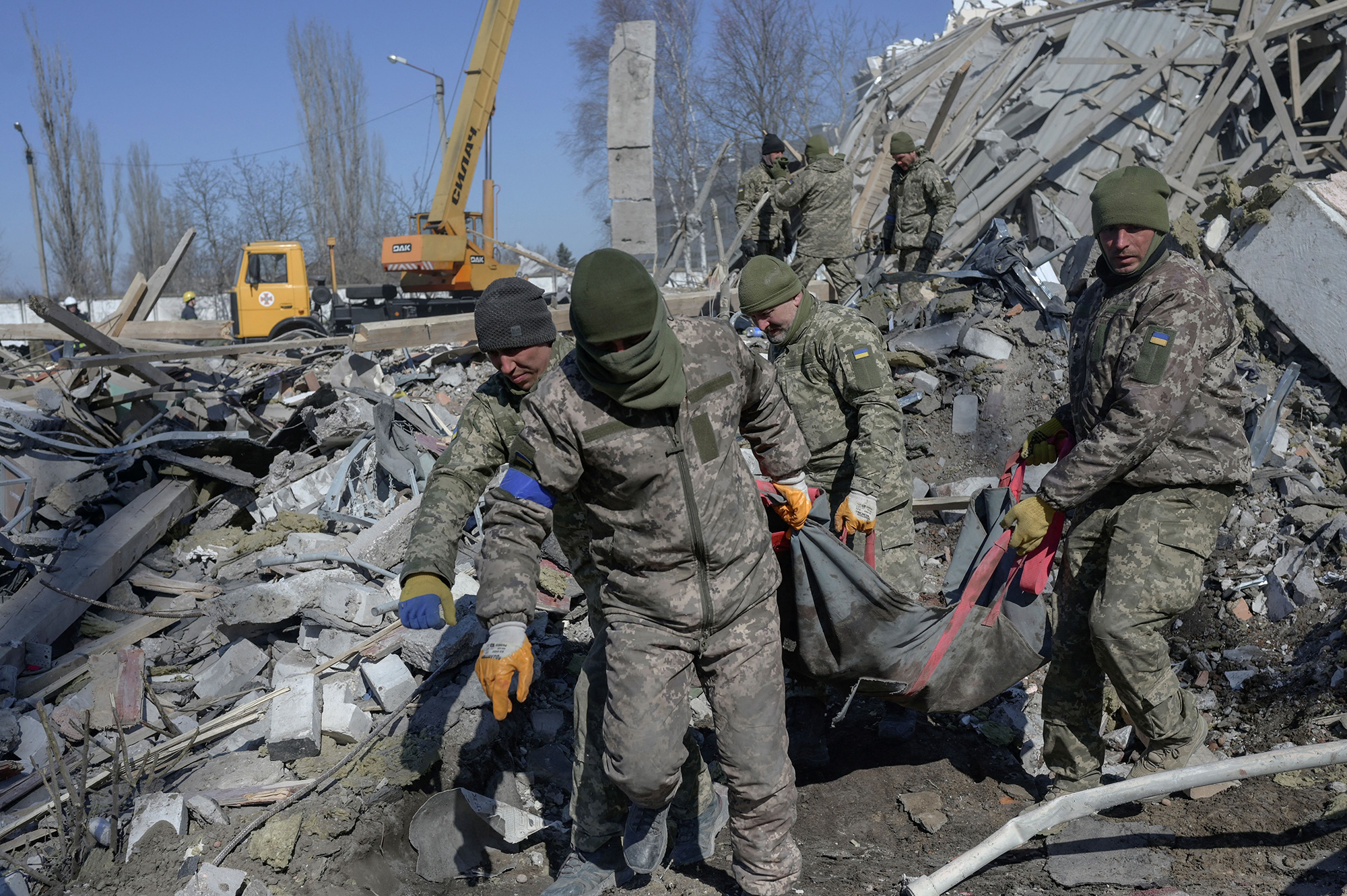 Ukrainian soldiers carry the body of a soldier through debris at the military school hit by Russian rockets the day before, in Mykolaiv, Ukraine, on March 19.