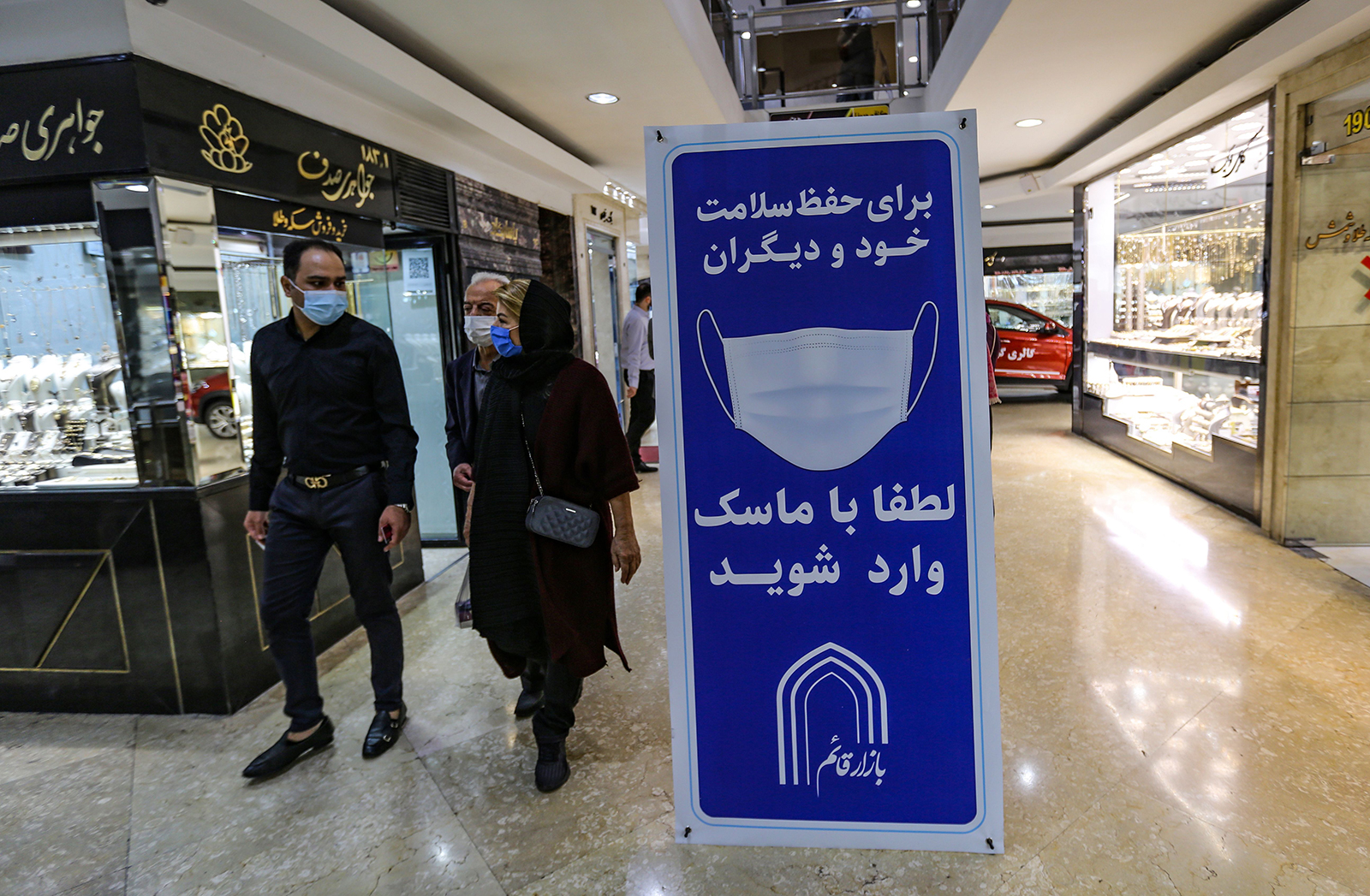 Iranians walk next to a sign advising people to wear masks on their way to shop in Tajrish square in the capital Tehran on November 1.