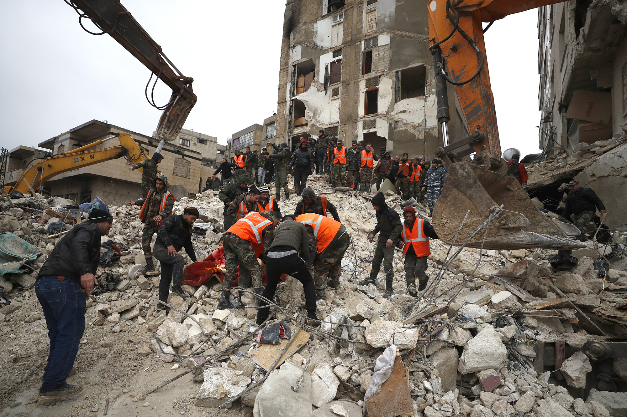 Civil defense workers and security forces search through the wreckage of collapsed buildings in Hama, Syria.