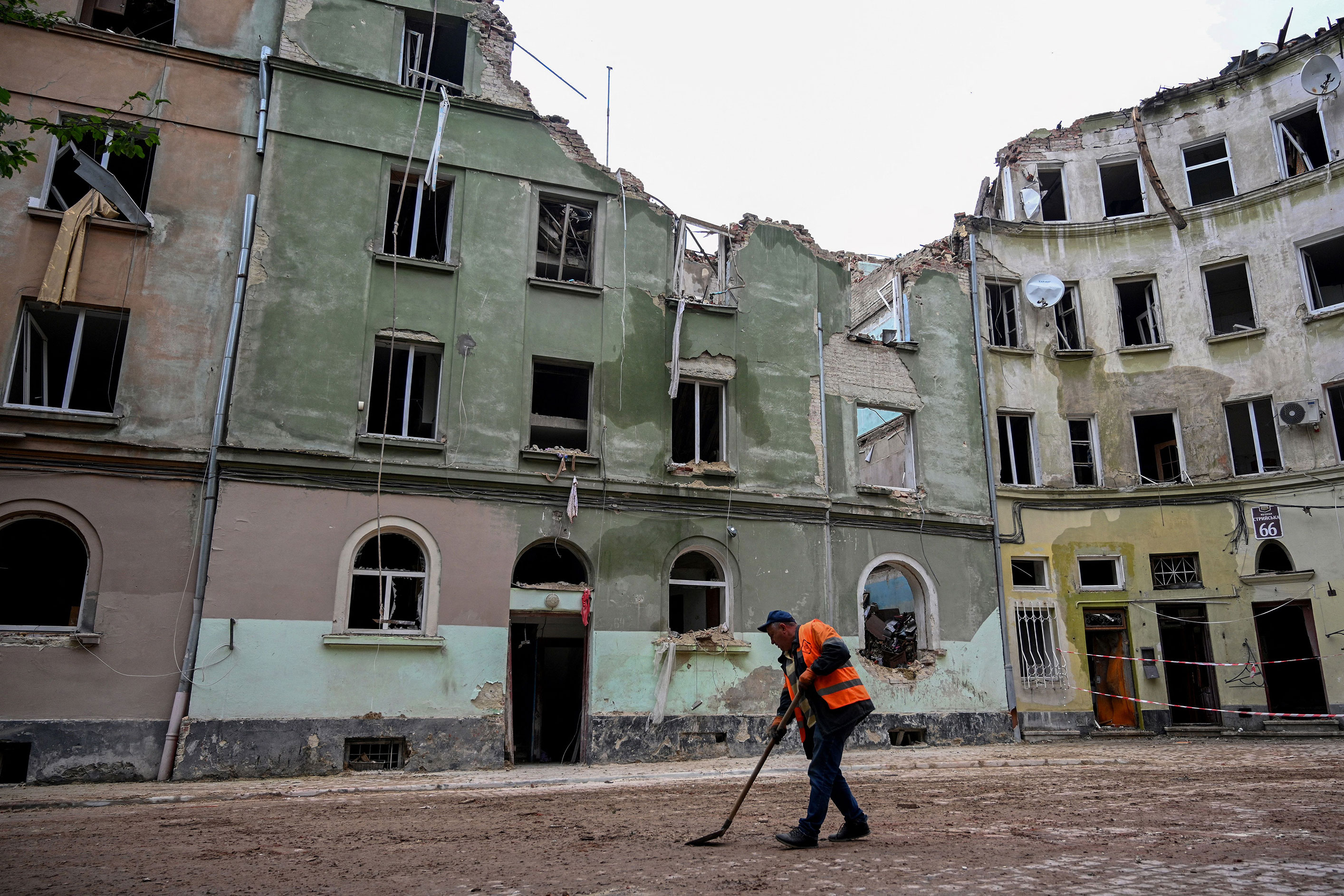 A worker sweeps outside an apartment building in Lviv on July 7, a day after it was partially destroyed by a missile strike. 