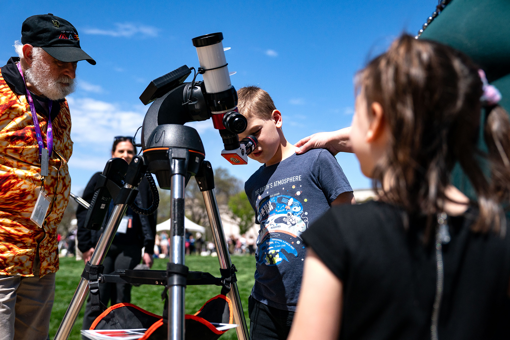 People look through a telescope that is tracking the path of the sun during the partial solar eclipse in Washington, DC. 