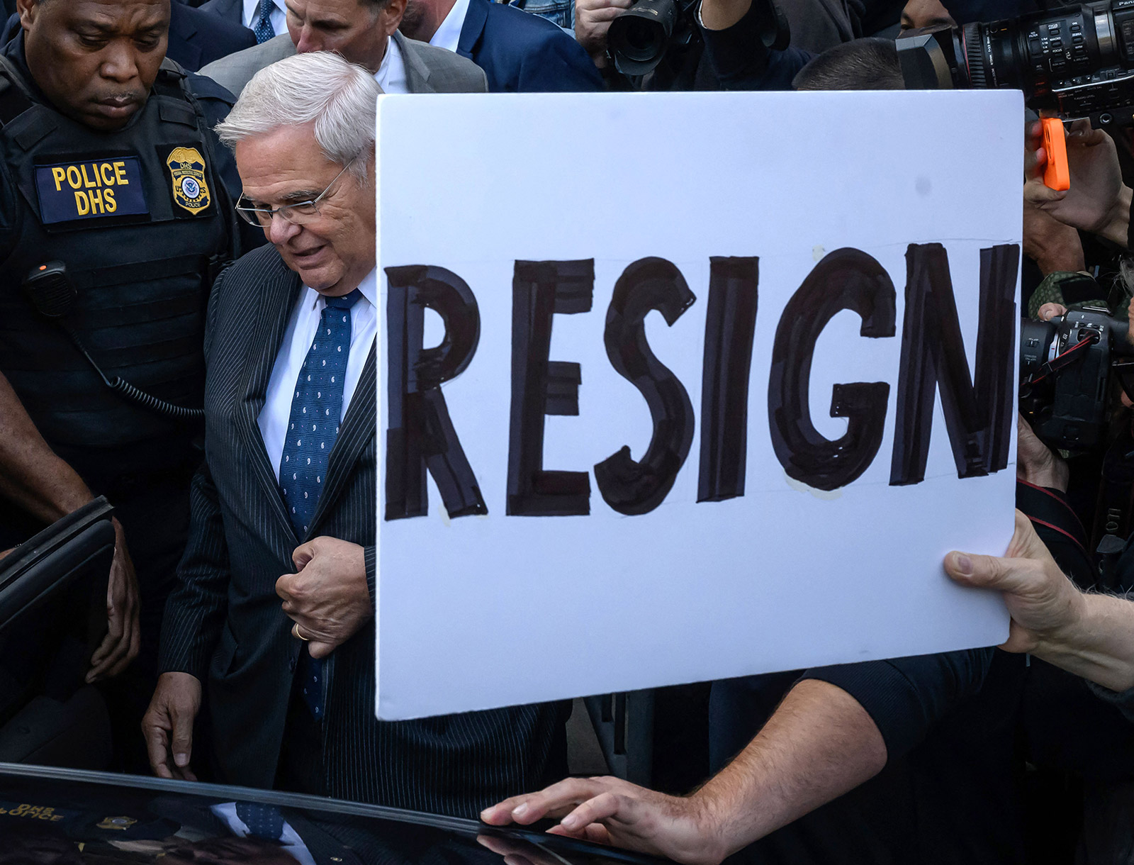 A demonstrator holds up a sign calling for Sen. Bob Menendez to resign as the New Jersey lawmaker departs the Manhattan courthouse on Wednesday.