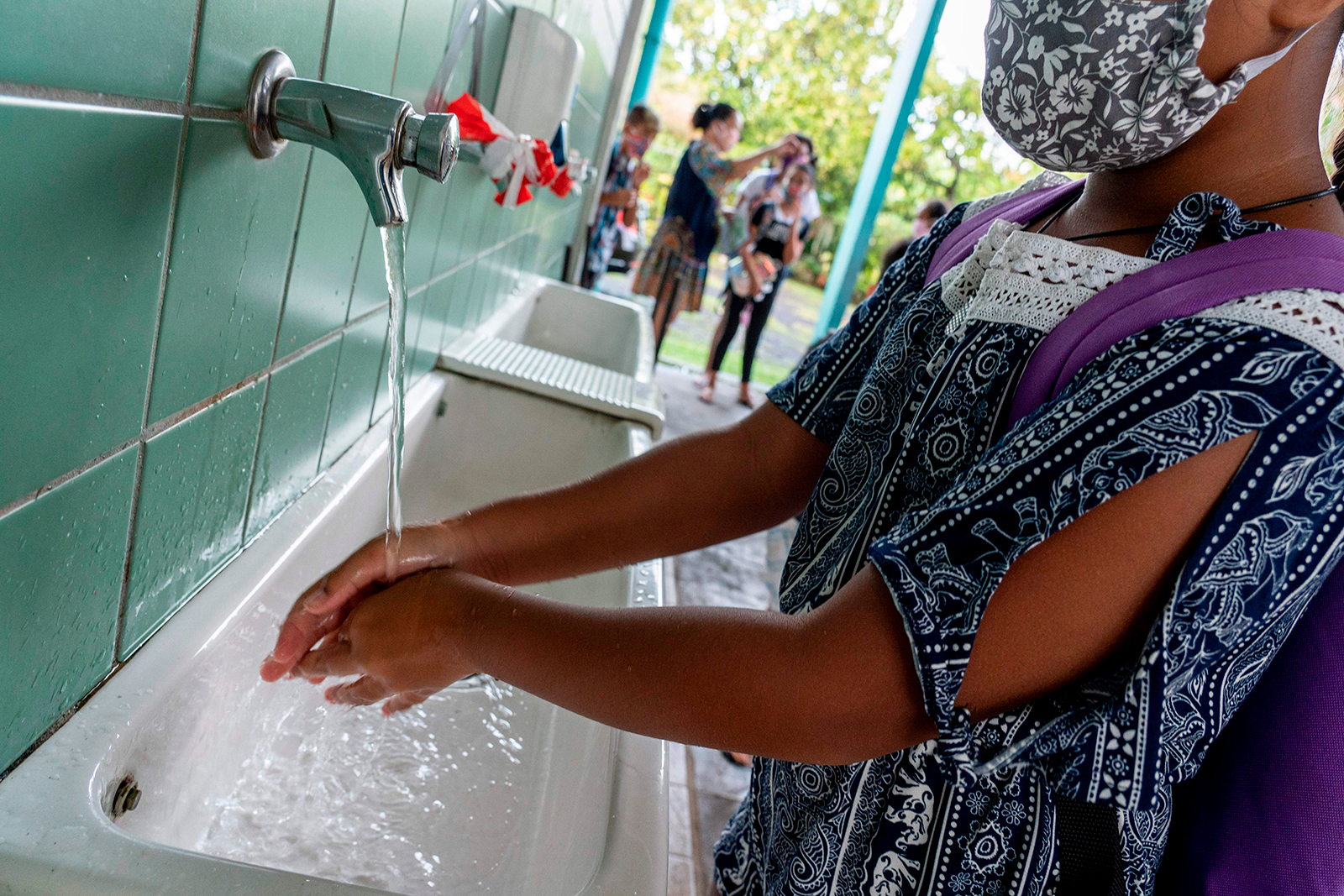 A schoolgirl wearing a protective face mask washes her hands as she arrives at the Taimoana Primary school in Papeete, on the French Polynesia island of Tahiti, on Monday, May 18.