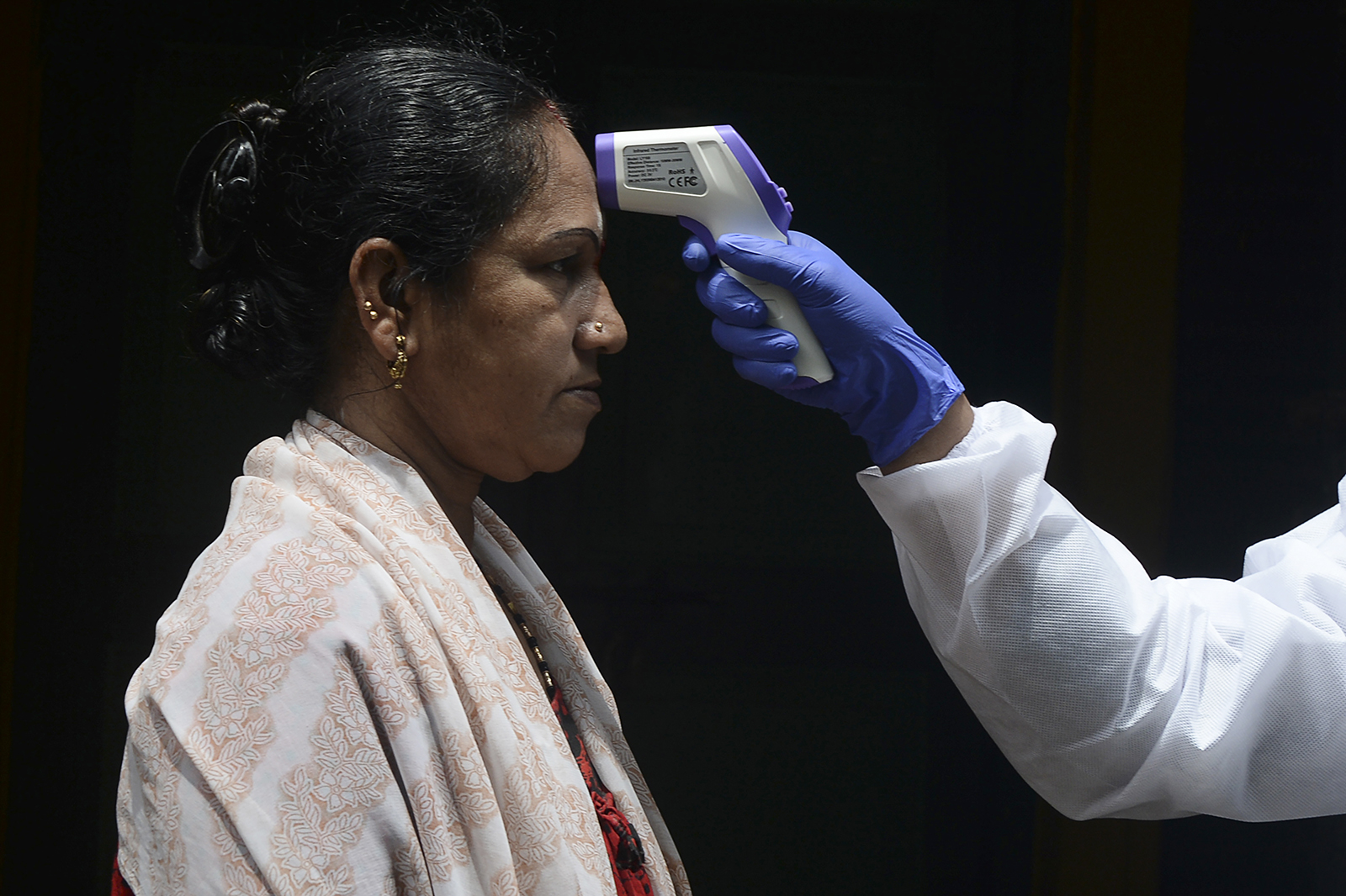 A doctor checks a woman's temperature at her residence during a government-imposed lockdown in Chennai, India, on June 29. 