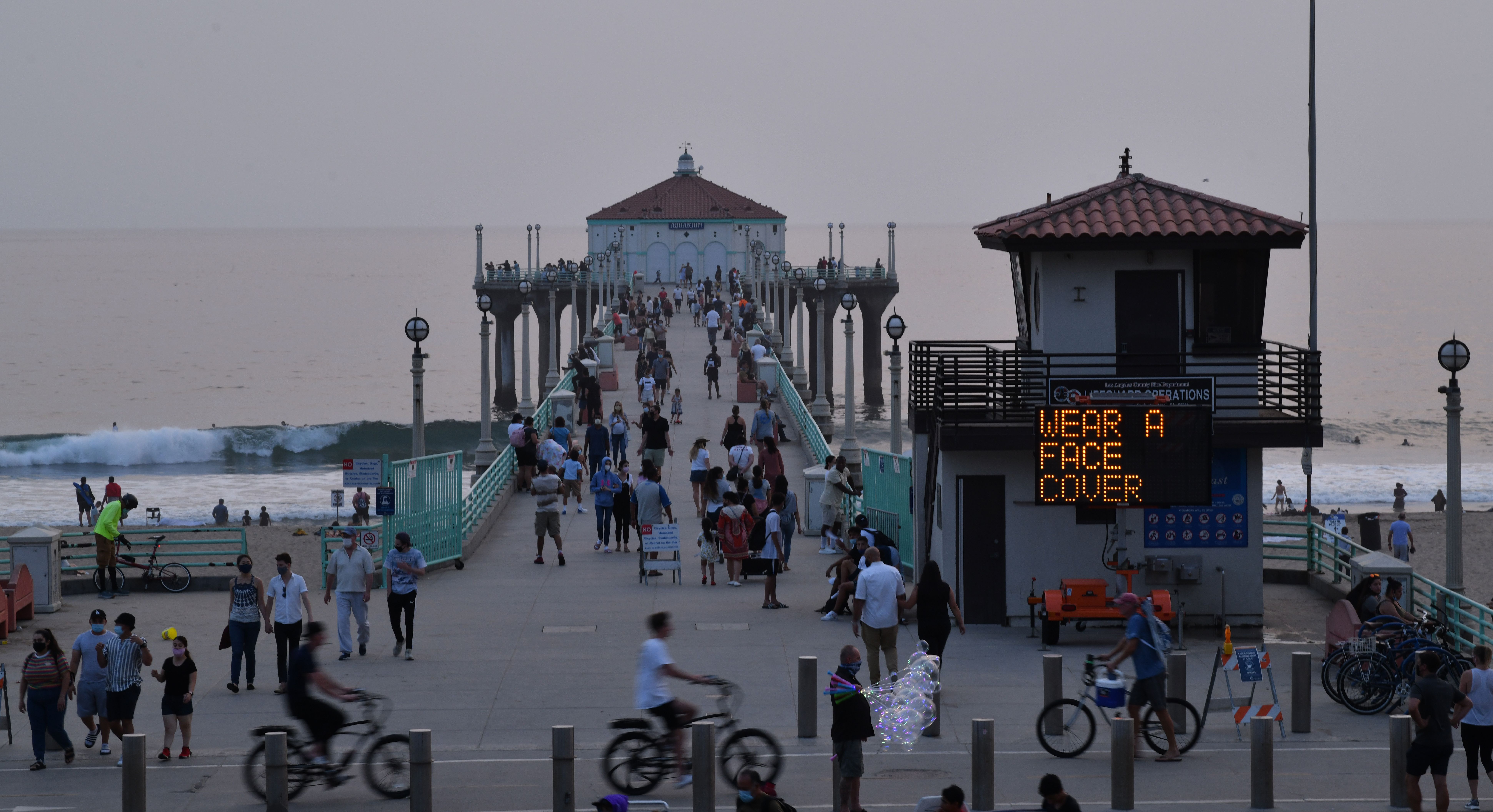 A sign reminding people to wear masks is seen by the pier on September 7 in Manhattan Beach, California.