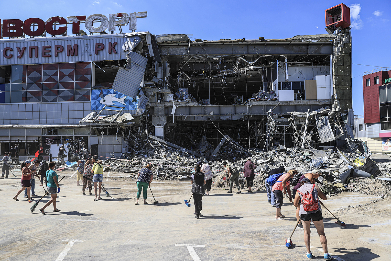 People sweep debris at a shopping mall destroyed by shelling in Kharkiv, Ukraine on June 8.