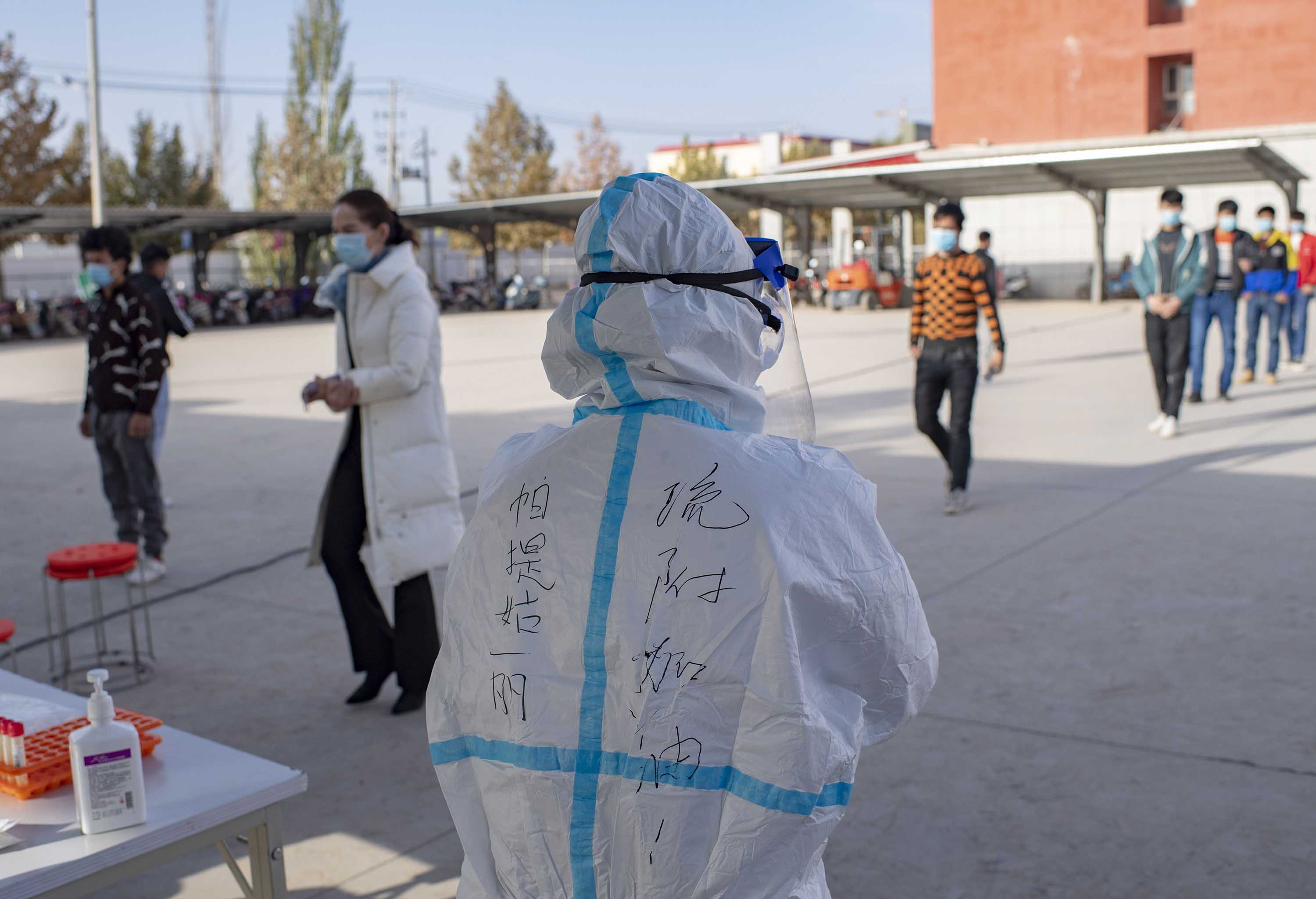 A medical worker stands by as people line up to be tested for Covid-19, in Kashgar Prefecture, in China's far-western Xinjiang region, on October 26.