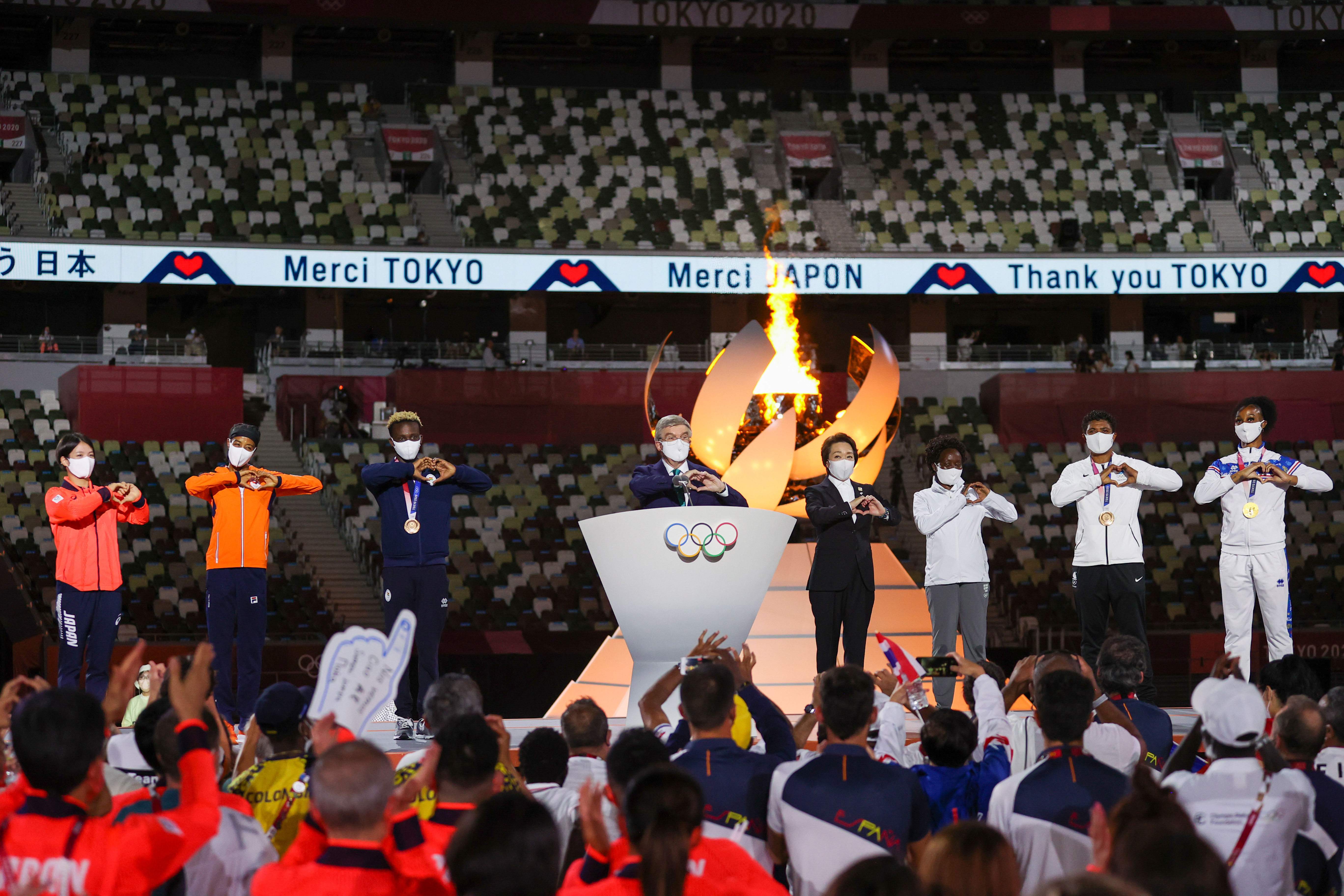 International Olympic Committee President Thomas Bach, center, and others on stage each form a heart with their hands during the closing ceremony.