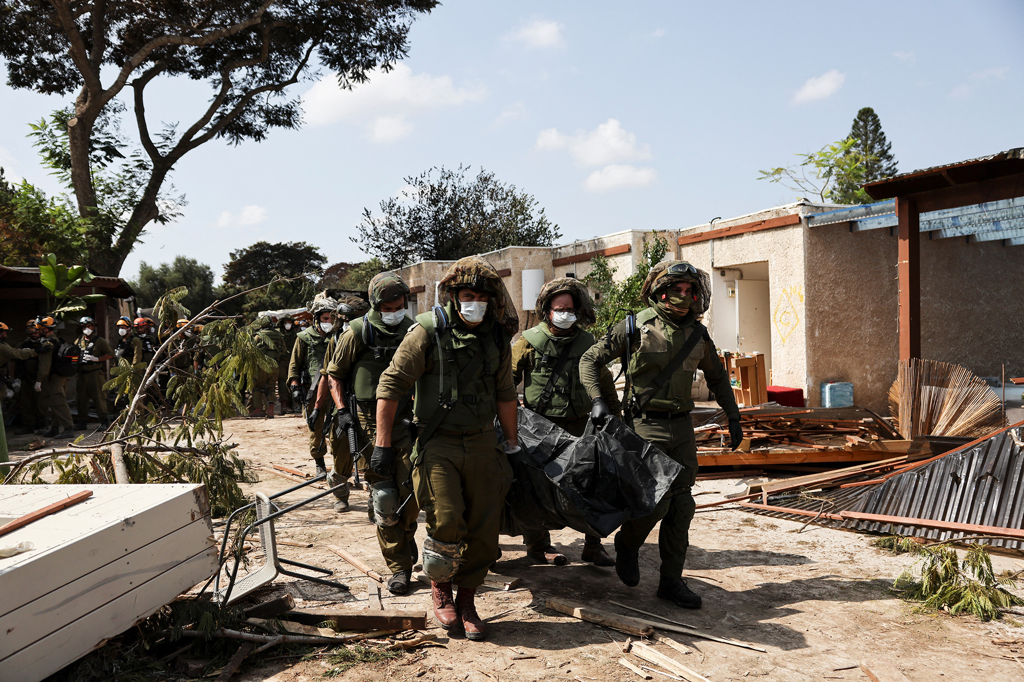 Israeli soldiers carry the body of a victim of an attack at Kibbutz Kfar Aza, in southern Israel, on October 10.