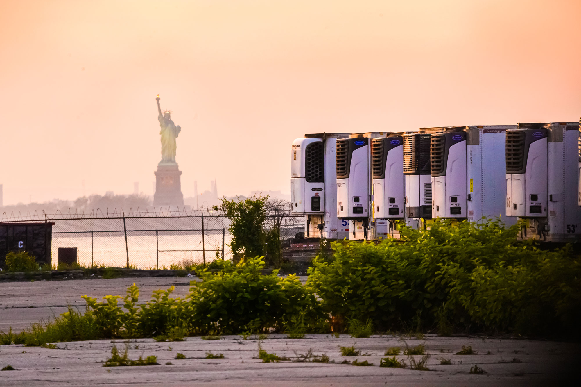 The Statue of Liberty is seen behind refrigeration trucks that function as temporary morgues at the South Brooklyn Marine Terminal during the coronavirus pandemic on May 25 in New York City.  