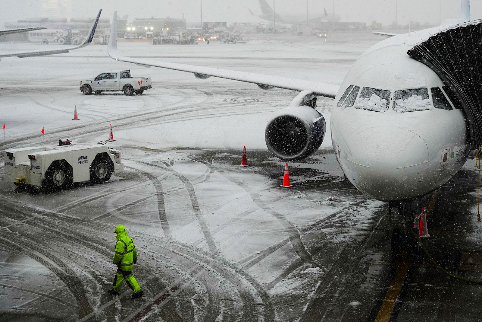 A man walks near a plane as snow falls at John F. Kennedy International Airport on Tuesday in New York. 