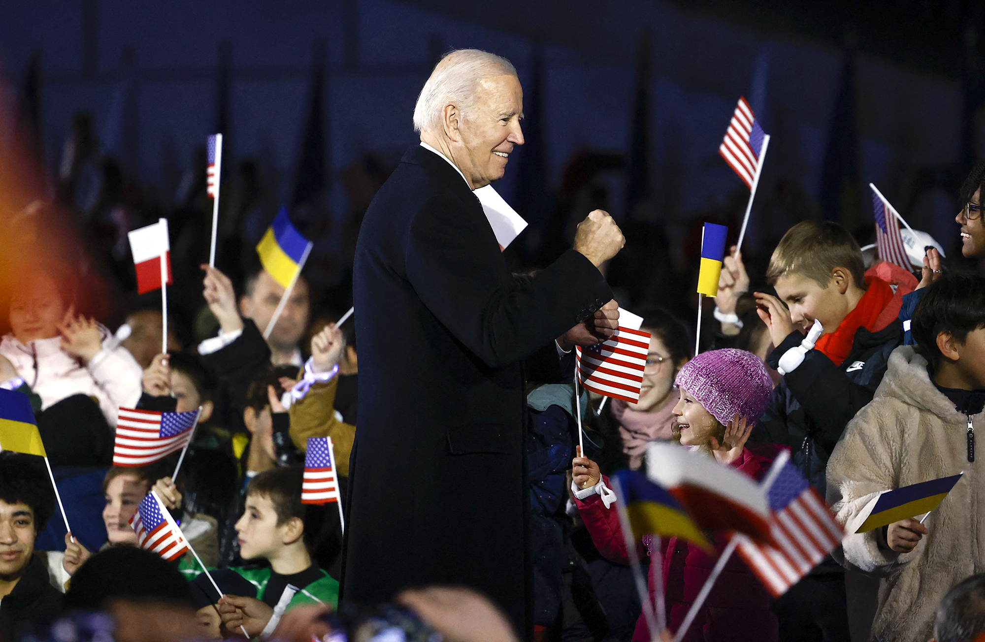 US President Joe Biden stands amid children cheering with US, Polish and Ukrainian flags after he delivered a speech in front the Royal Warsaw Castle Gardens in Warsaw, Poland on February 21.