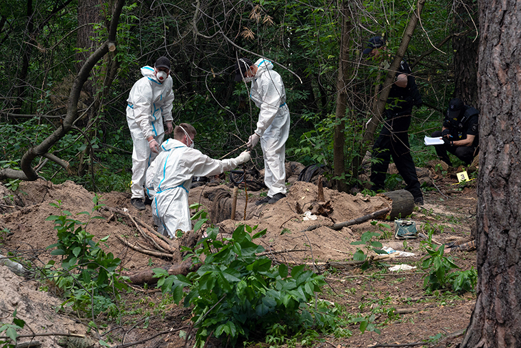 Investigators work on June 13, at the scene where bodies of civilians killed by Russian soldiers were found near the village of Myrotske in Bucha district. 