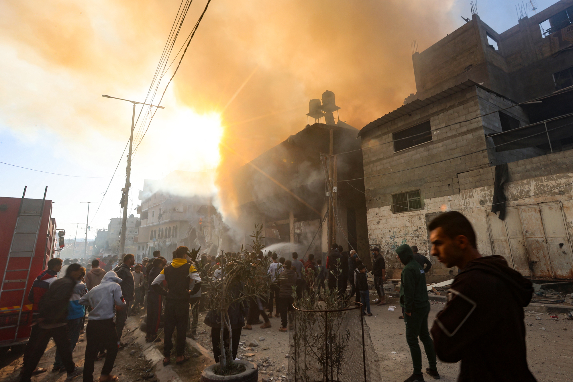 People gather in front of a burning building after it was hit by an Israeli strike in Khan Younis, southern Gaza, on December 9.