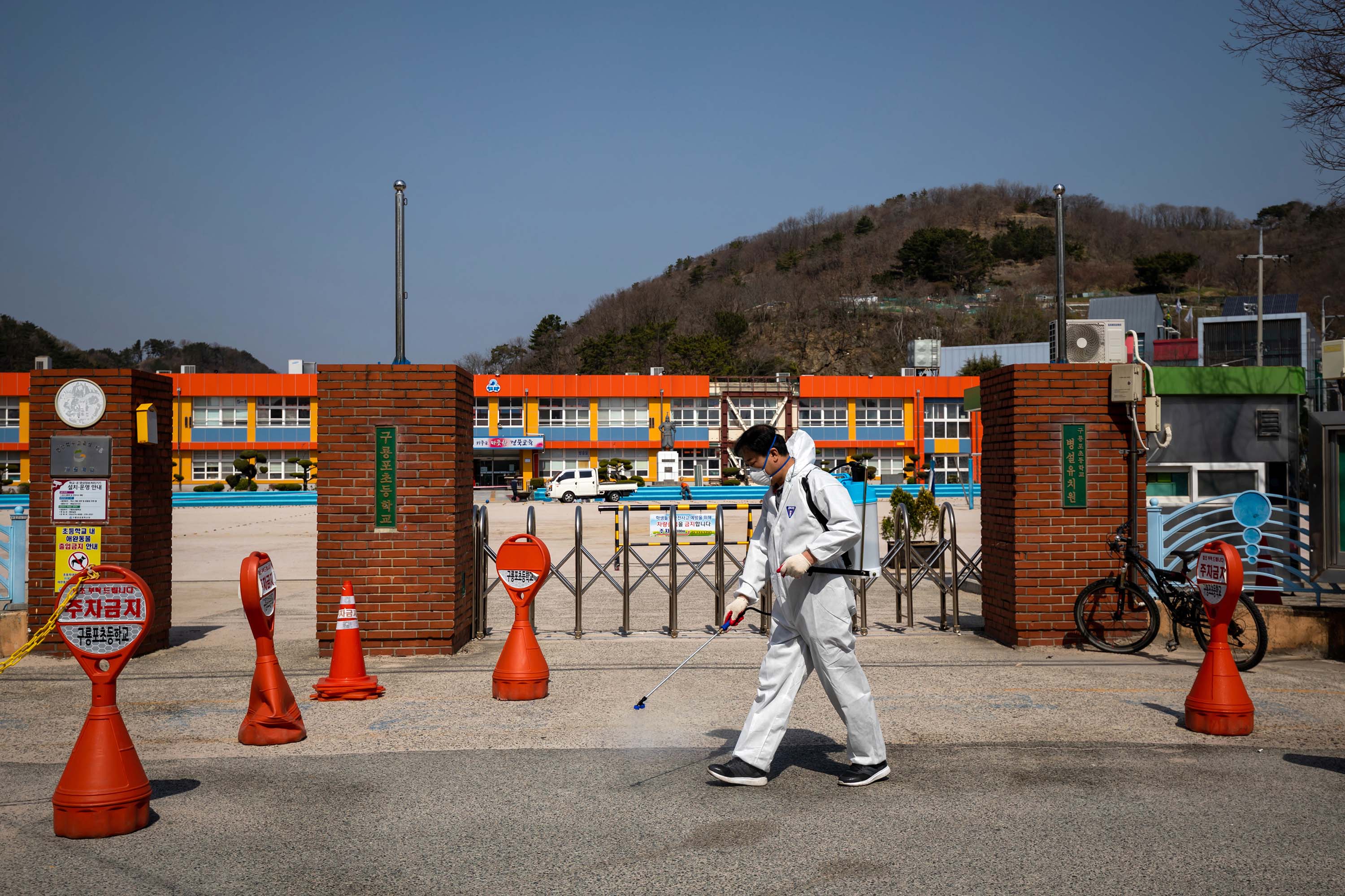 A volunteer sprays disinfectant outside an elementary school in Pohang, South Korea, on March 21.