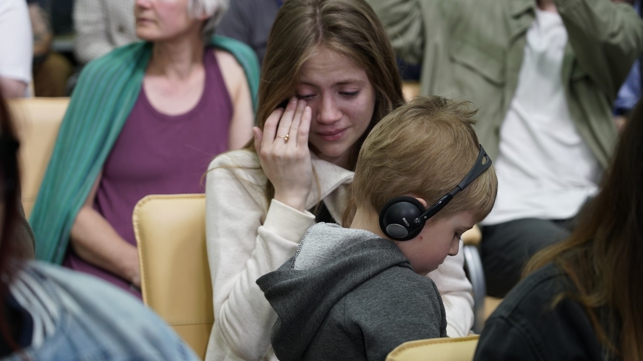 21-year-old Nicole wipes away tears at a briefing about soldiers in Mariupol's Azovstal plant, as her 5-year-old nephew Kirill sits on her lap. She said that yesterday, she found out one of her good friends had died in the plant. 