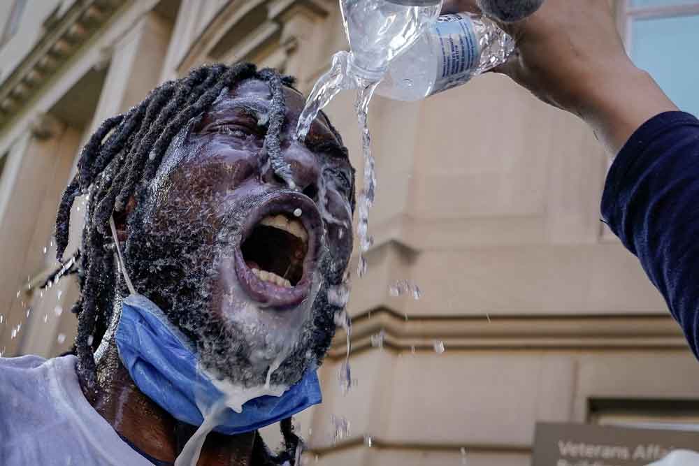 A demonstrator is doused with water and milk after being hit with pepper spray from law enforcement during a protest on June 1 in downtown Washington.