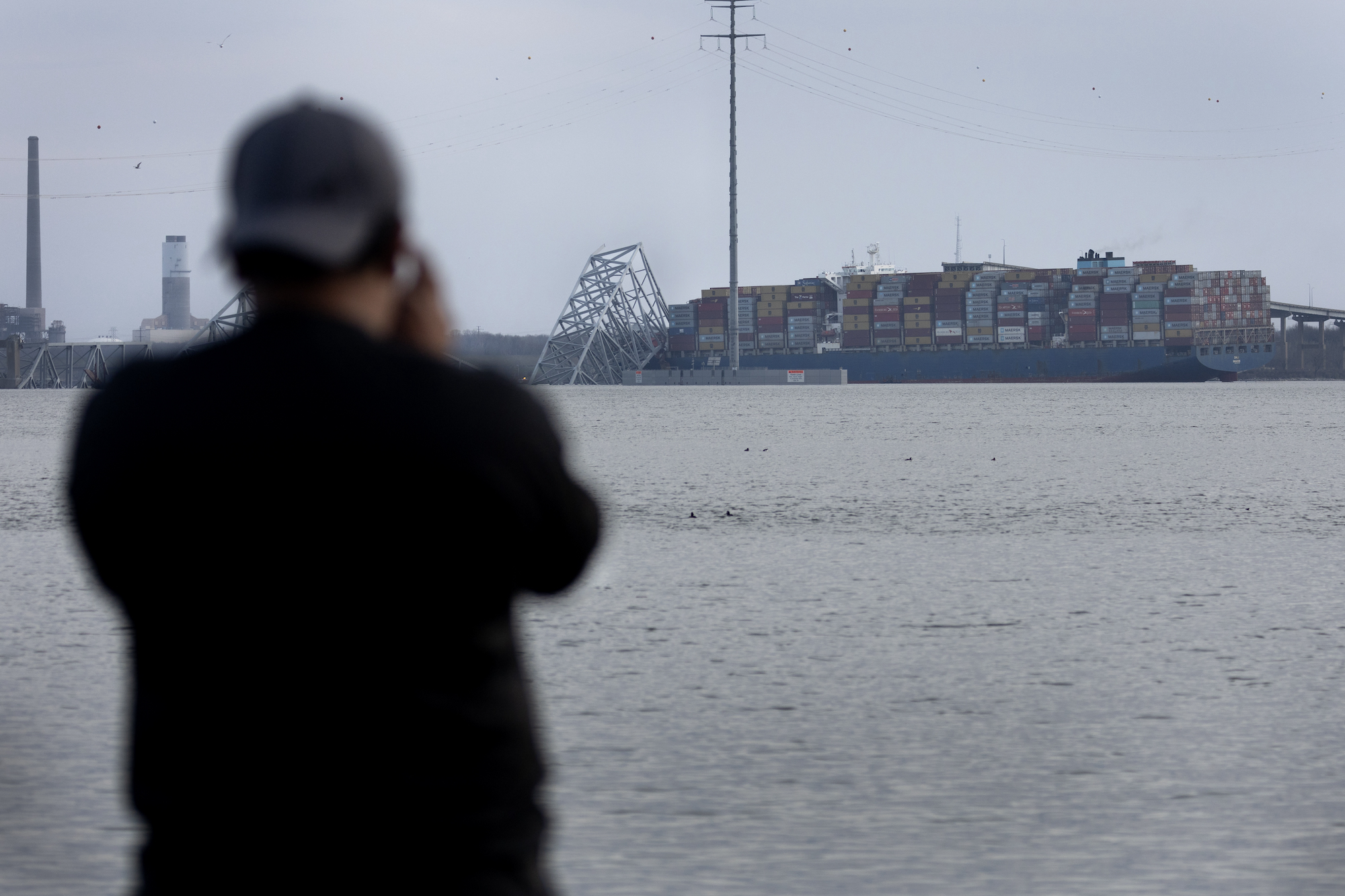 A man tries to photograph the cargo ship that hit and collapsed the Francis Scott Key Bridge in Baltimore on Tuesday.