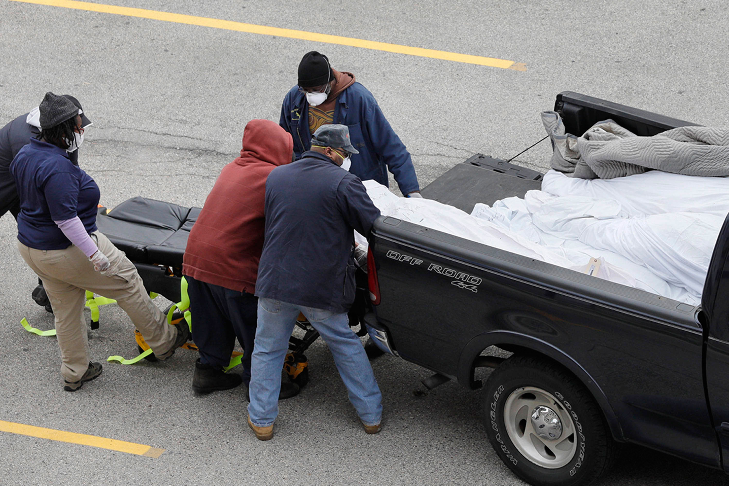 Workers move a body from the back of the truck onto a gurney, in an area near the Joseph W. Spellman Medical Examiner Building, in Philadelphia, on April 19.