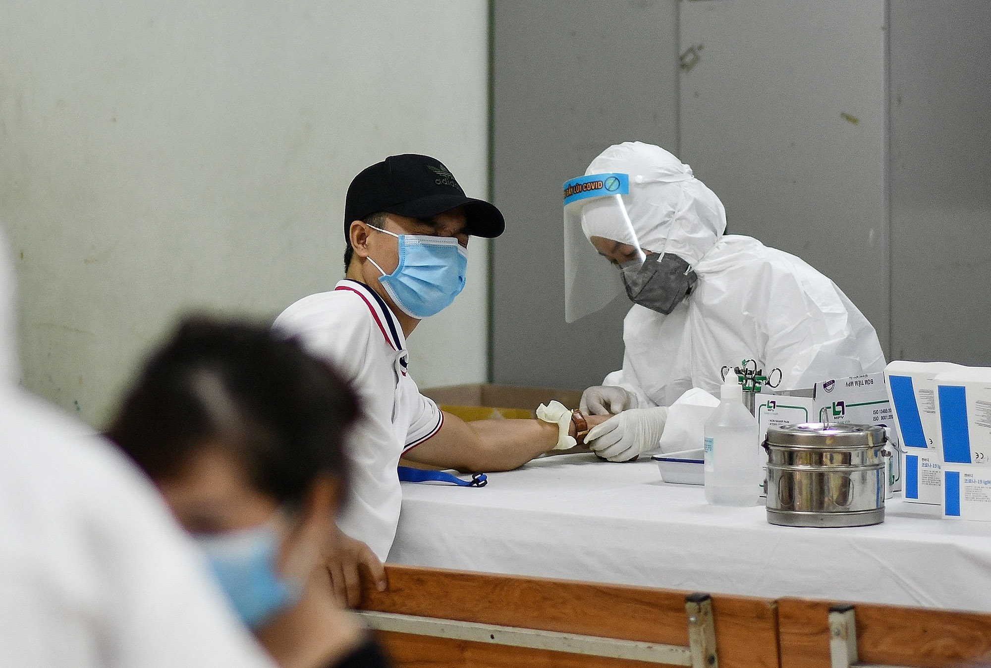 A man grimaces as health workers collect his blood sample at a Covid-19 rapid testing center in Hanoi, Vietnam, on August 1. 