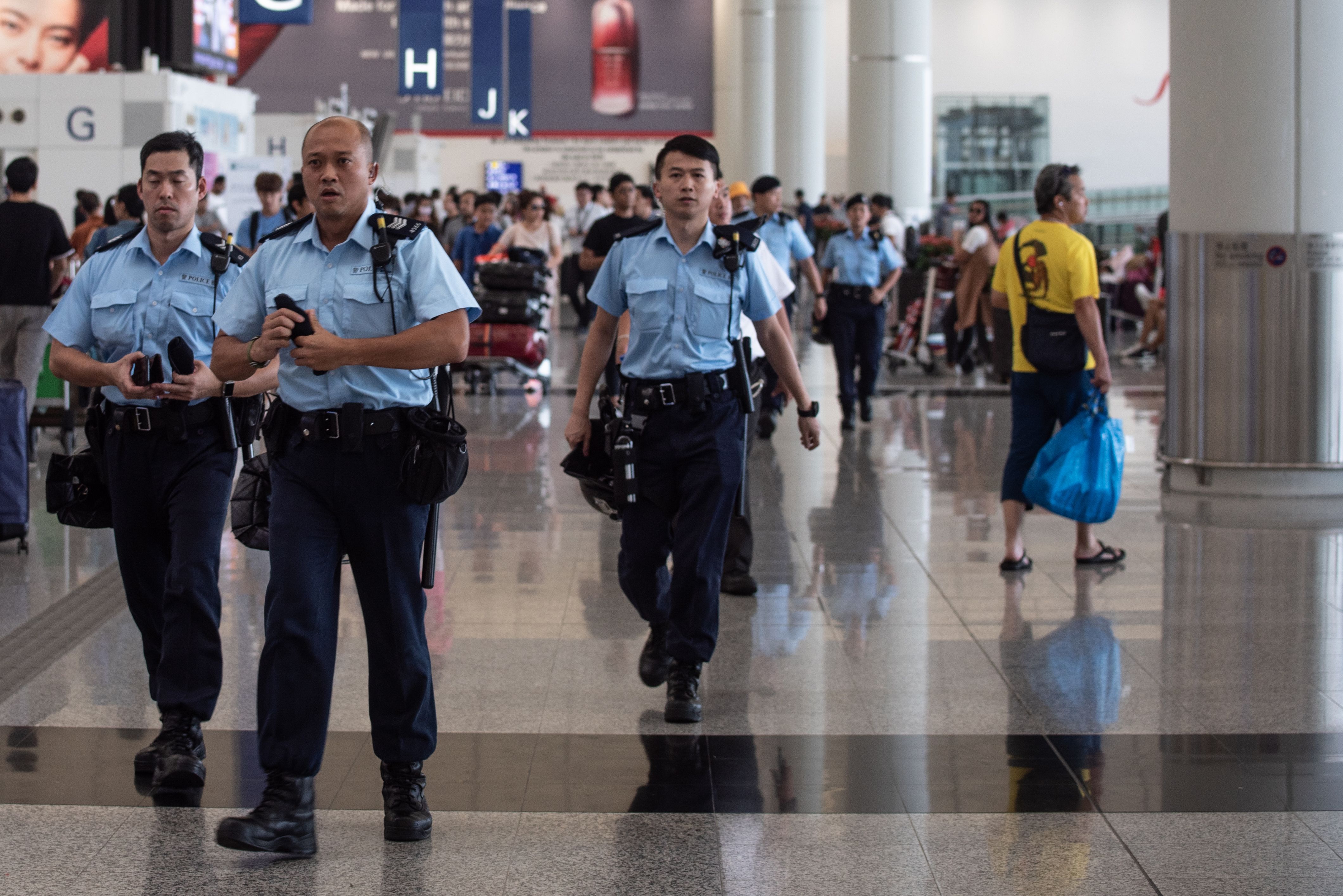 Police officers patrol in the departures hall of Hong Kong's International Airport on August 14, 2019.