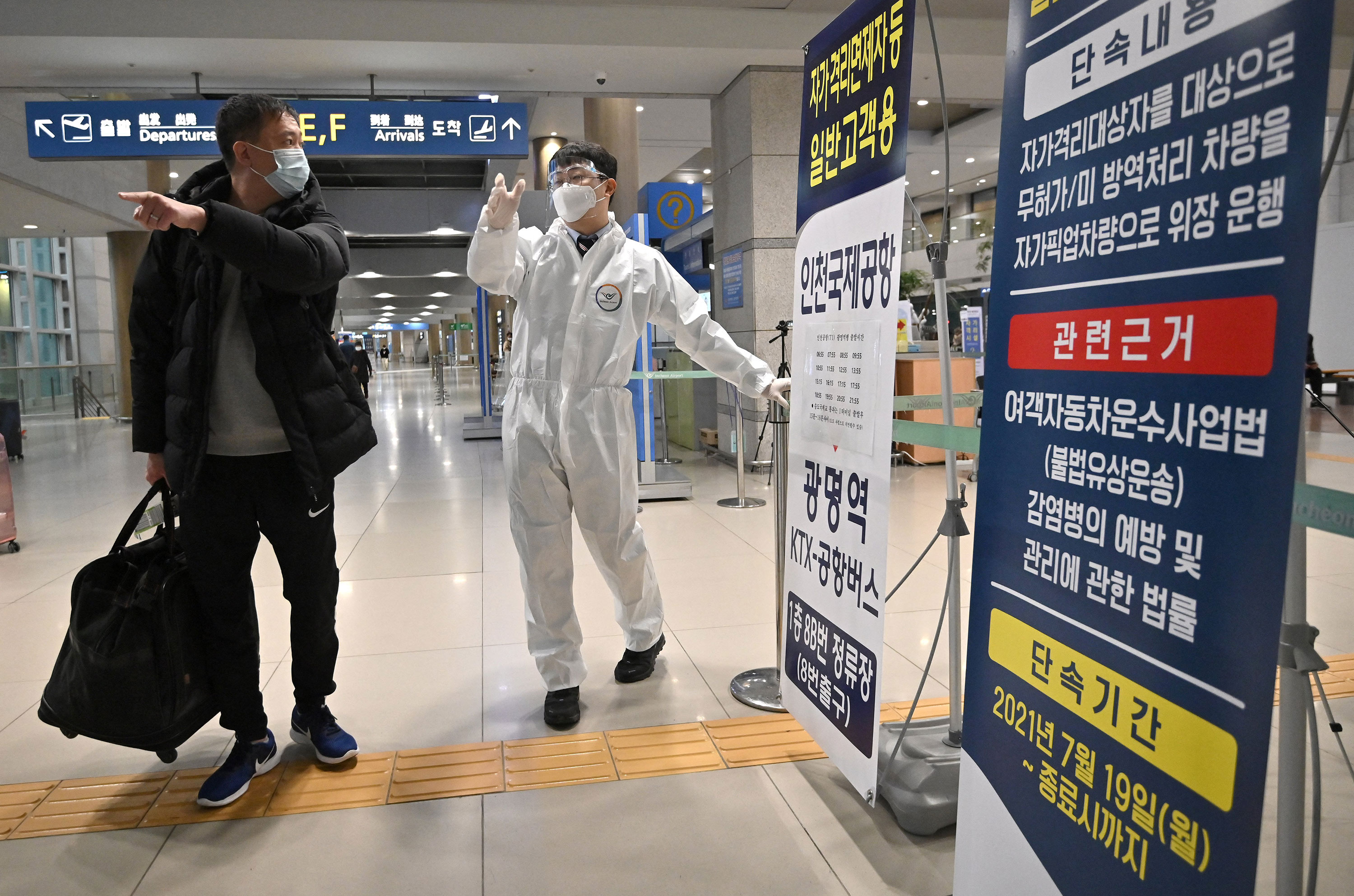 A staff member wearing protective equipment guides a traveller at the arrival hall of Incheon International Airport in Incheon, South Kora, on November 30.