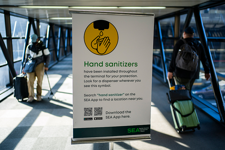 Travelers pass by a sign advertising hand sanitizer at Seattle-Tacoma International Airport on November 29, 2020 in SeaTac, Washington.