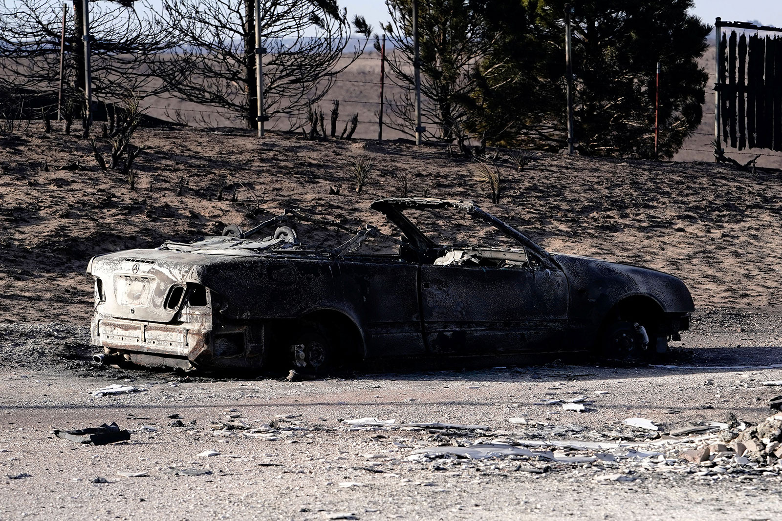 The remains of a vehicle sit in the driveway of a home that was destroyed by the Smokehouse Creek wildfire.