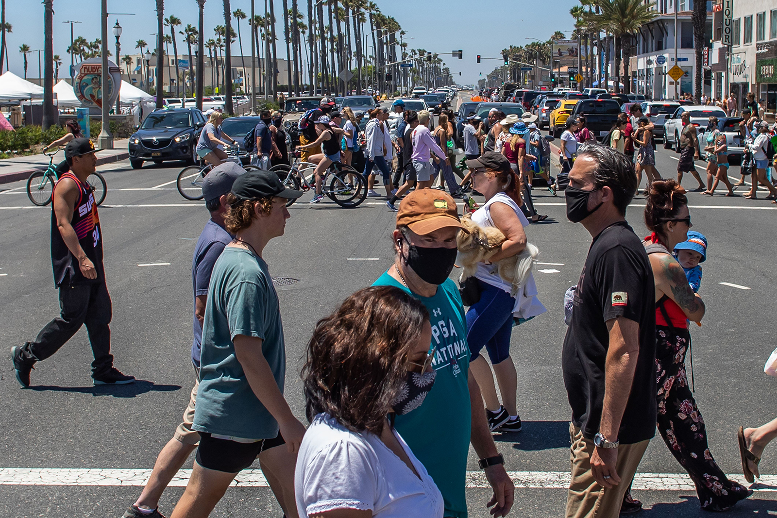 People cross the street in Huntington Beach, California, on Sunday, July 19.