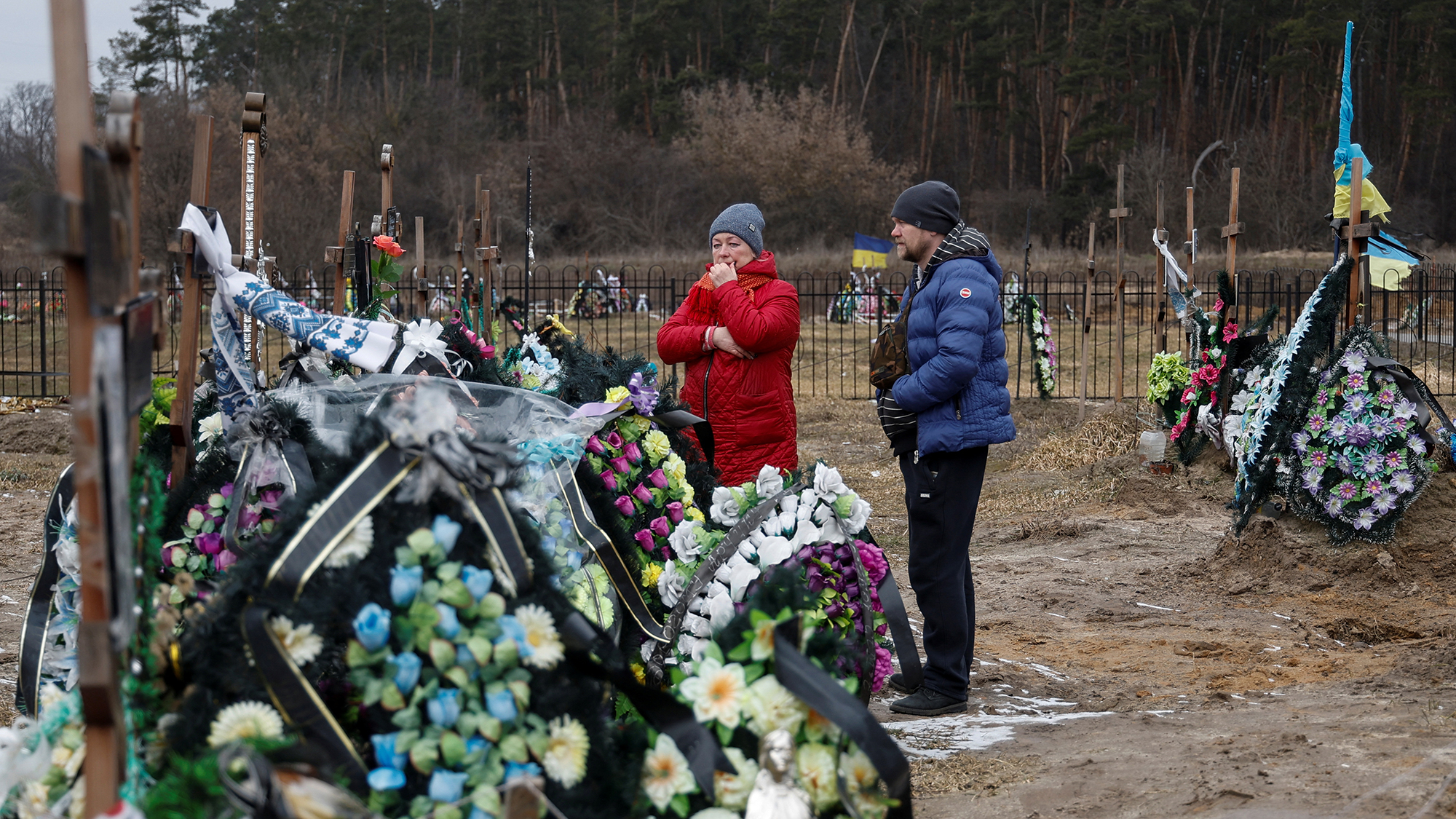 Wife Natalia and son Artem stand next to the grave of Vasyl Maznichenko, local resident killed by Russian soldiers during the occupation of Bucha, on the first anniversary of Russia's attack on Ukraine on Friday.