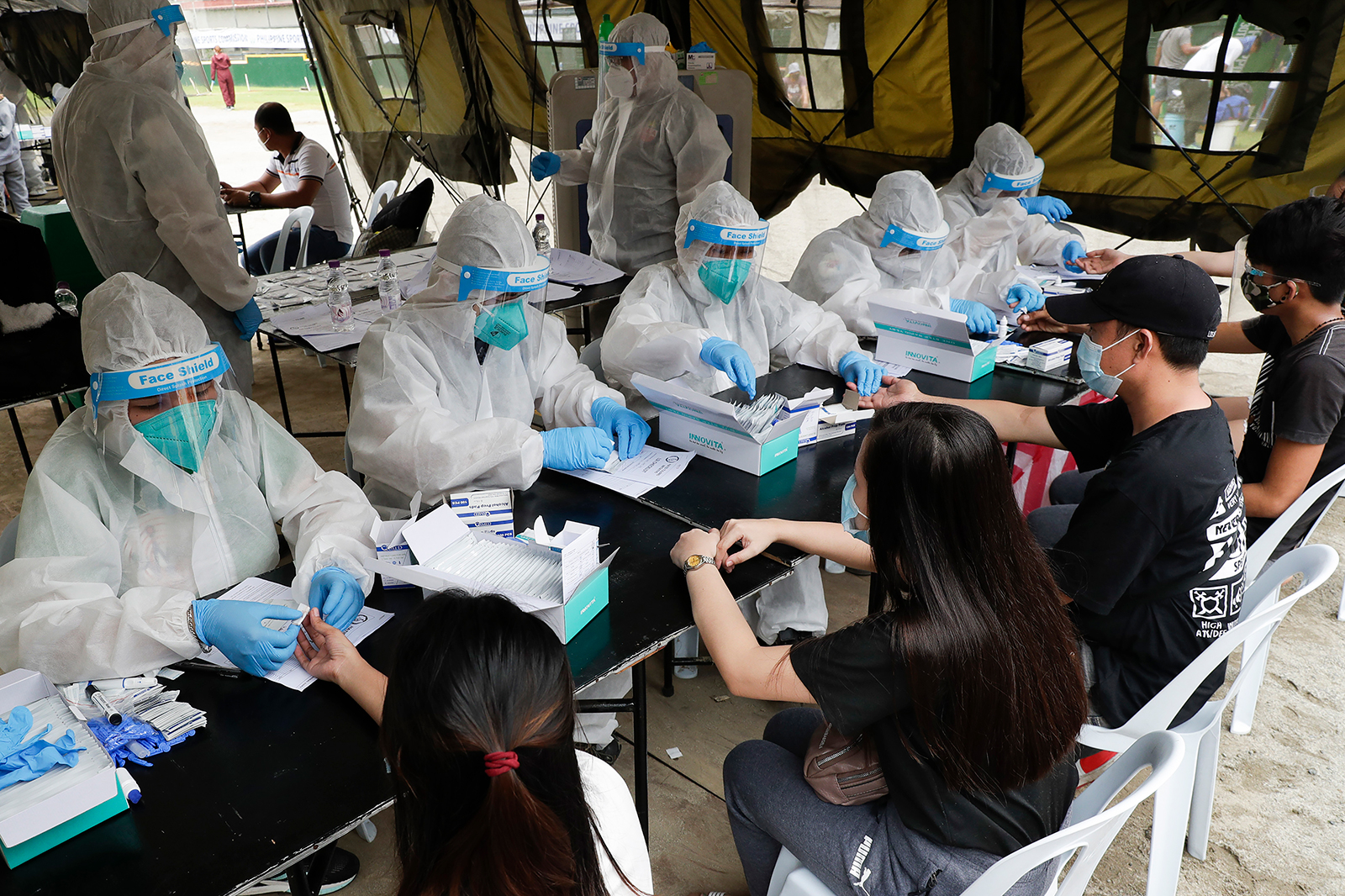 Health workers wearing protective suits perform coronavirus rapid tests on people in Manila, Philippines, on July 28