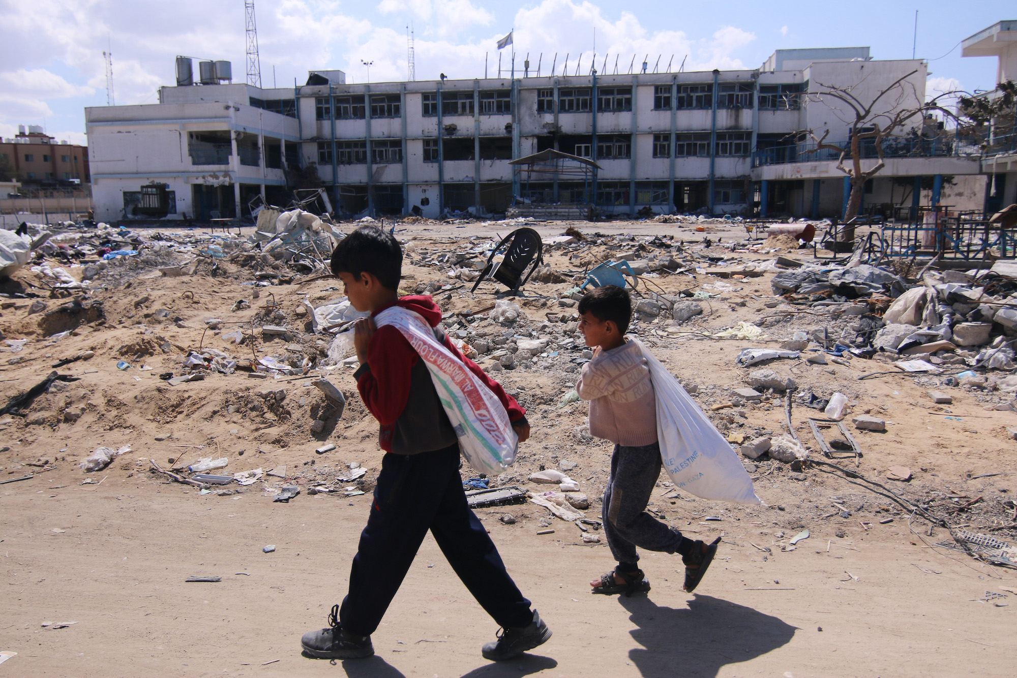 Palestinian children walk past rubble in Khan Younis, Gaza, on Friday.