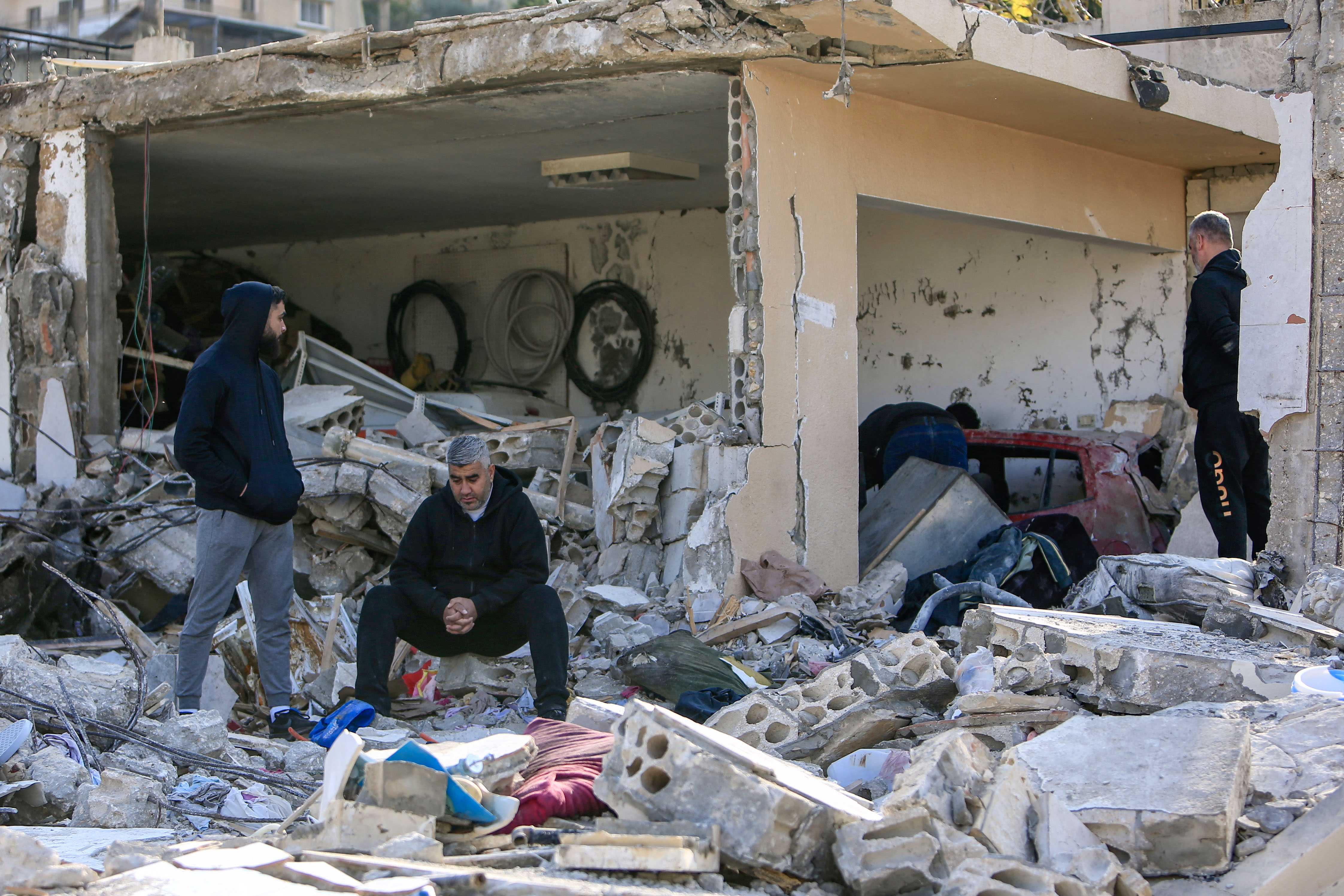 Men check the rubble of a building in Bint Jbeil, southern Lebanon, near the border with Israel, following Israeli bombardment the previous night, on December 27, 2023.