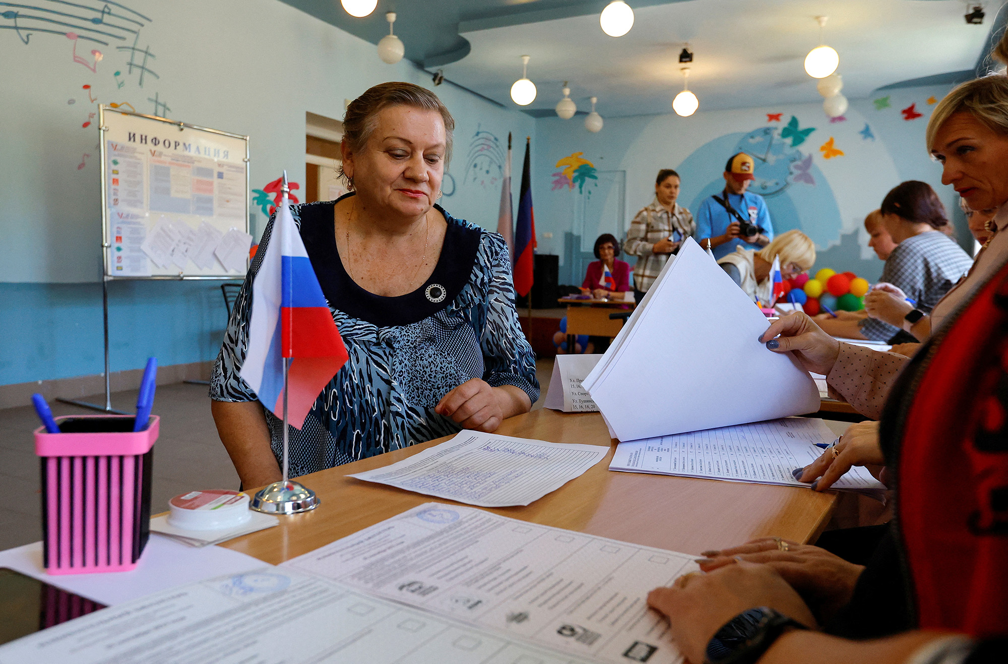 A voter sits in front of members of an electoral commission at a polling station during local elections held by the Russian-installed authorities in Donetsk, Russian-controlled Ukraine, on September 8.