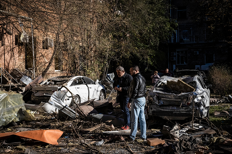 People look at their destroyed cars that stand amid damage caused by a missile strike in a residential area near Tower 101 not far from Kyiv's main train station on Tuesday, October 11, in Kyiv, Ukraine.