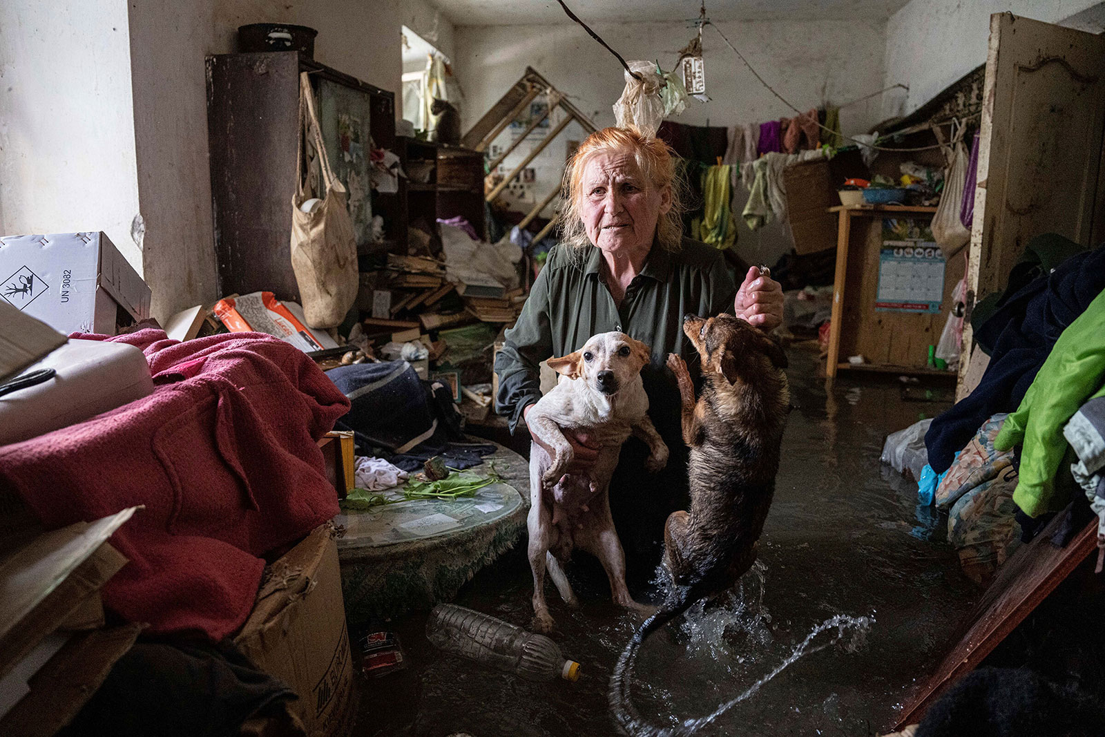 A woman holds her pets as she stands inside her flooded home in Kherson, Ukraine.
