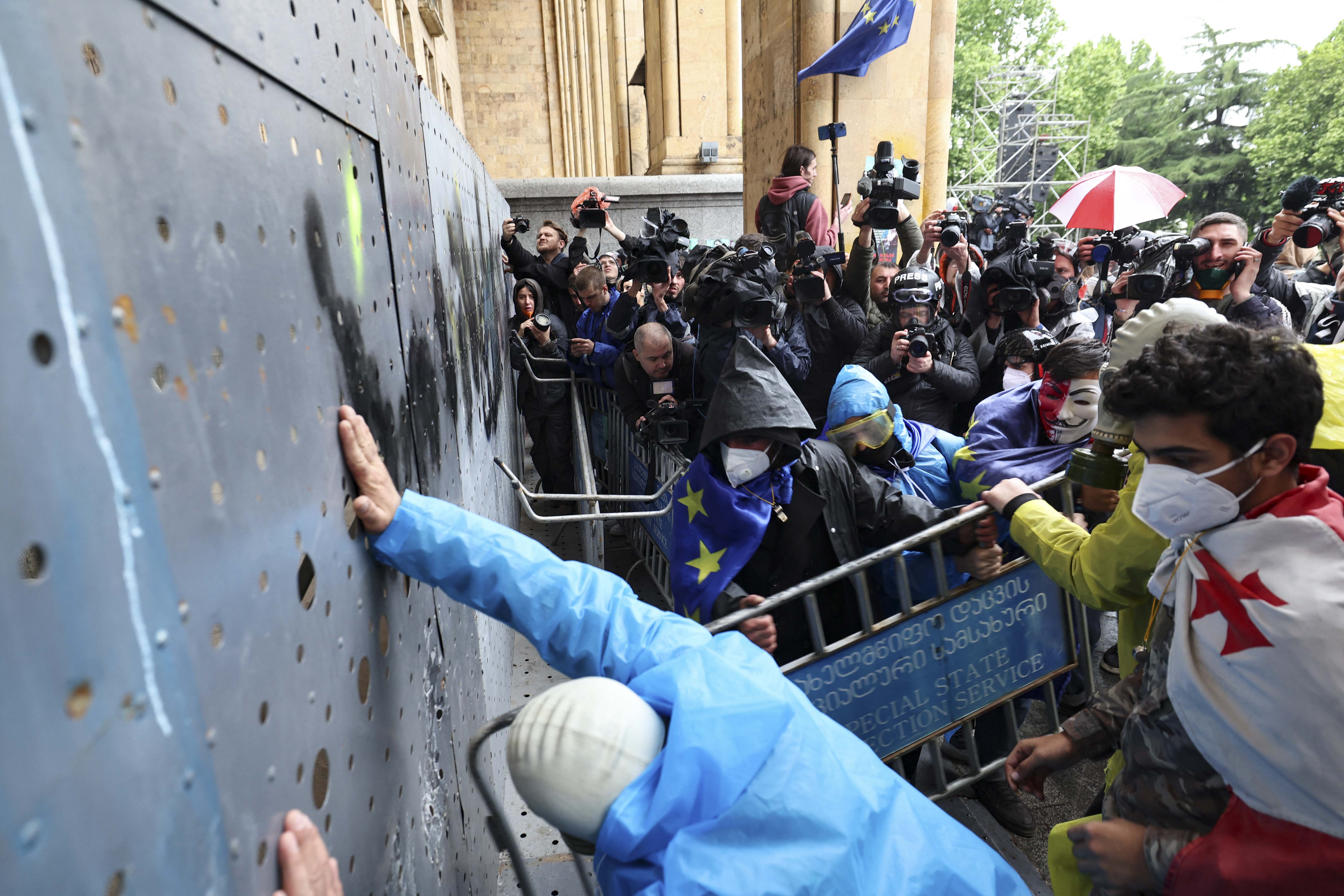 Georgian demonstrators attempt to break into the parliament through a metal barrier erected in front of its main gates, during a rally against the controversial "foreign influence" bill in Tbilisi, Georgia, on Tuesday, May 14. 
