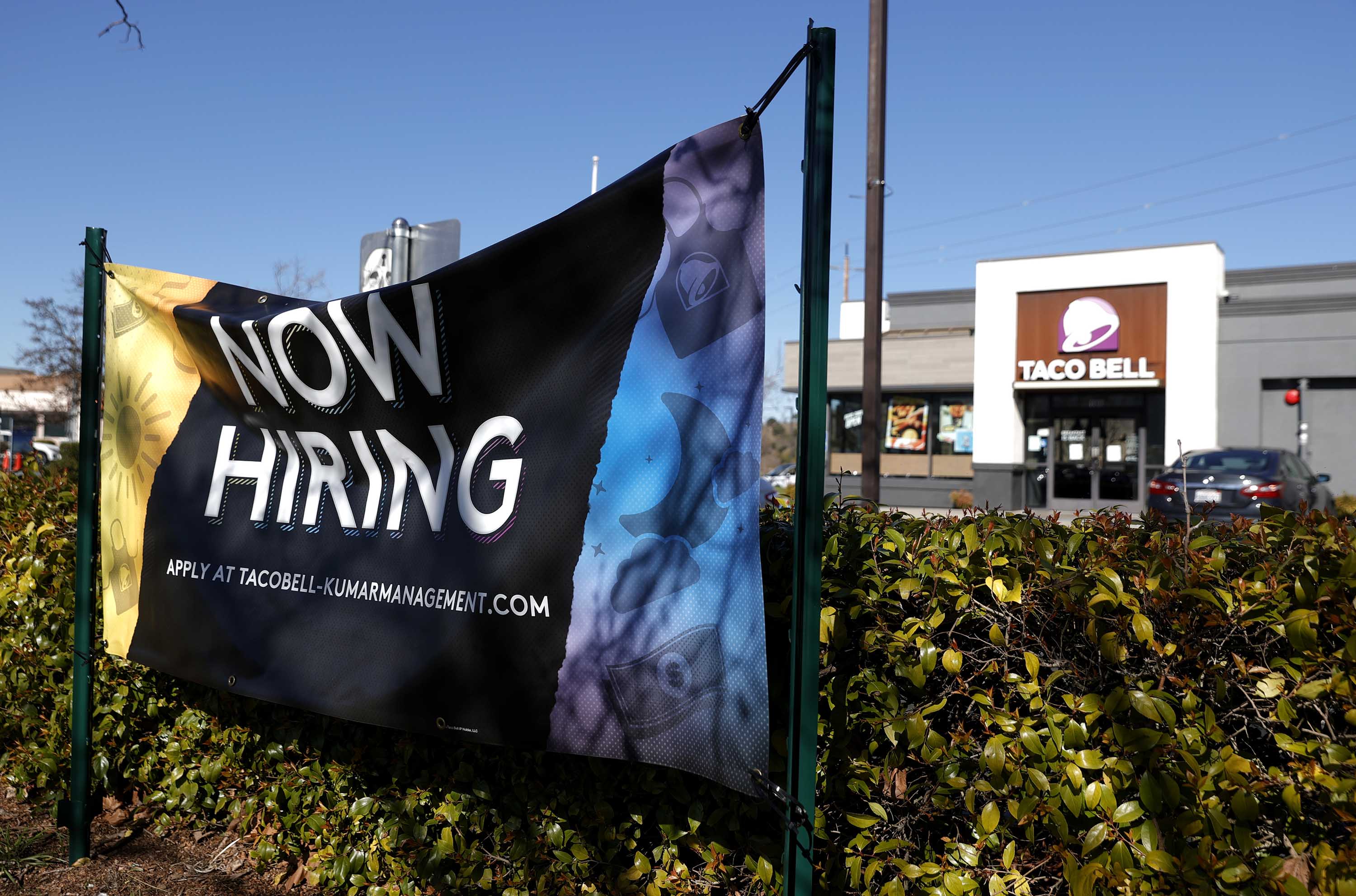 A 'now hiring' sign in posted in front of a Taco Bell restaurant on February 5, in Novato, California. 