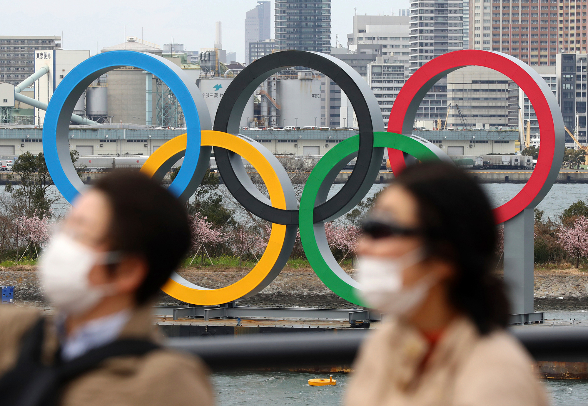 People walk near the Olympics rings in Odaiba, Tokyo on February 22.