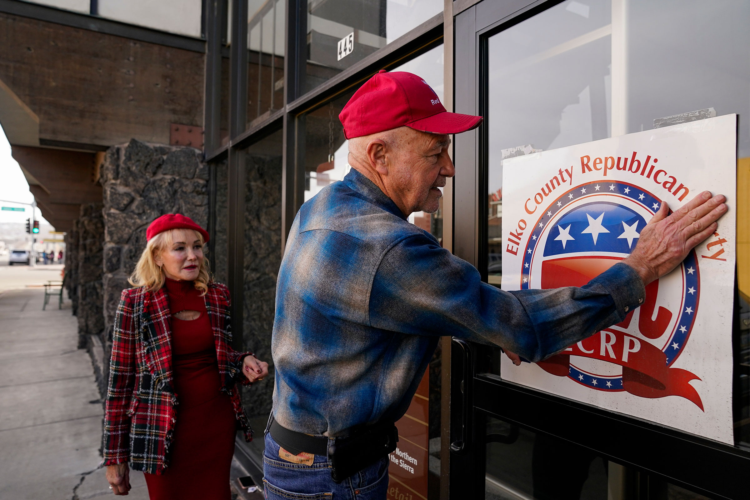 Lee Hoffman, right, tapes a sign for the Elko County Republican Party on the window of a building owned by Lina Blohm, left, on Saturday, December 16, 2023, in Elko, Nevada.