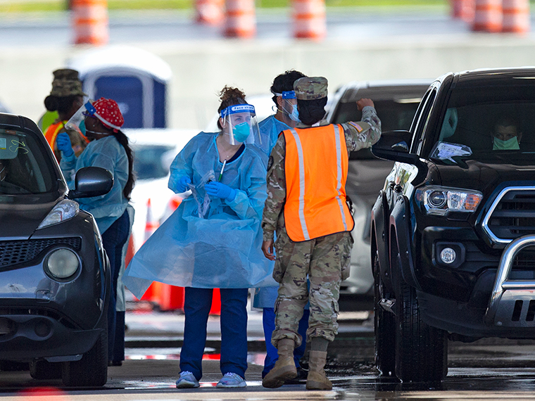 A National Guard troop directs cars as people are tested by healthcare workers at the COVID-19 drive-thru testing center at Hard Rock Stadium in Miami Gardens on Sunday, July 19. 