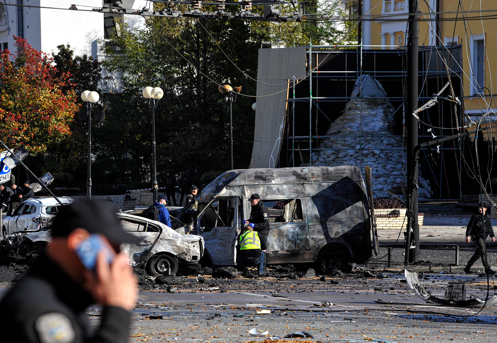 Police conduct an investigation near burned-out cars that were damaged following a rocket attack by the Russian army in Kyiv on October 10.