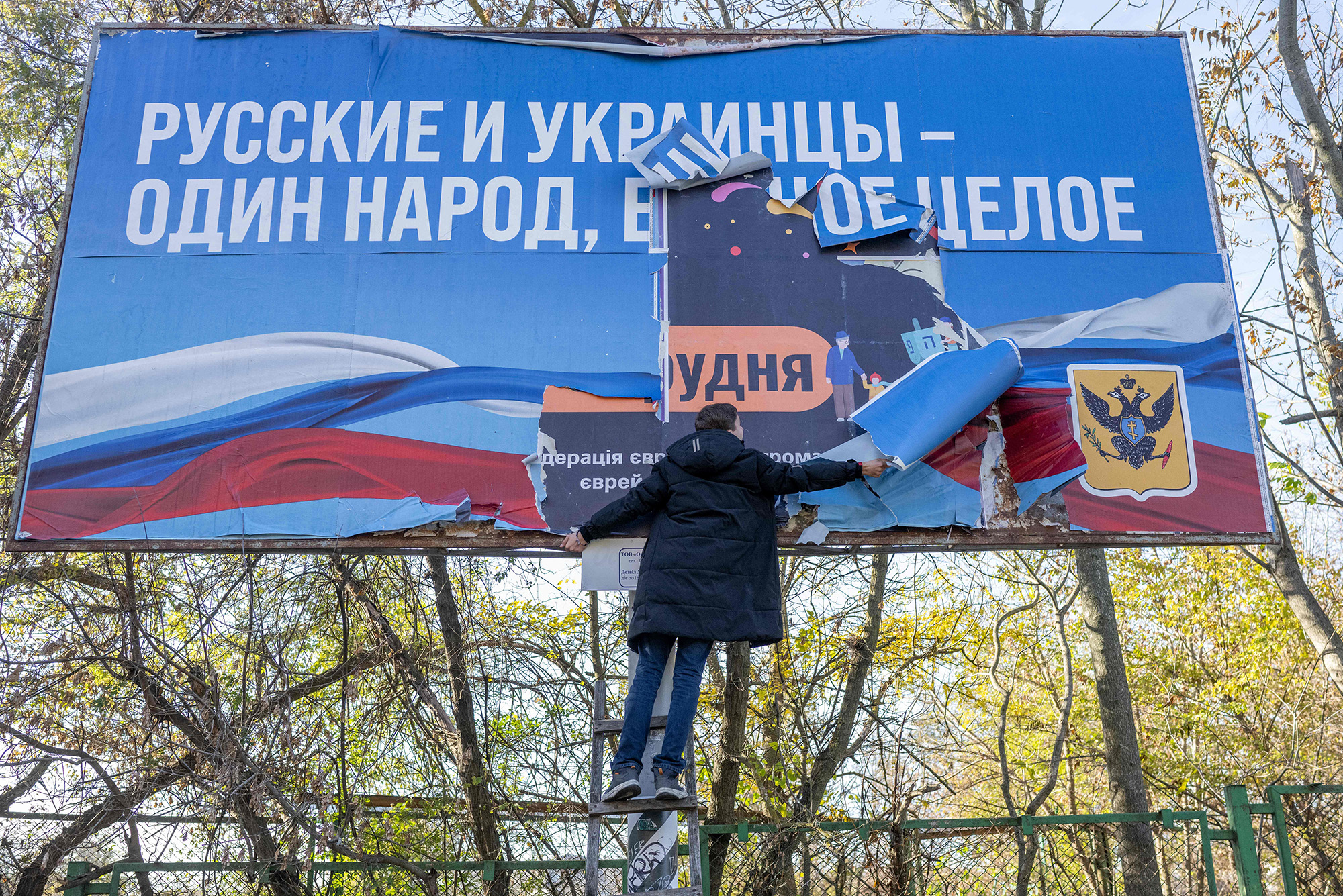 A man removes a banner from the Russian occupation period "Russians and Ukrainians are one people, one whole" in the newly liberated Kherson, Ukraine, on November 14.
