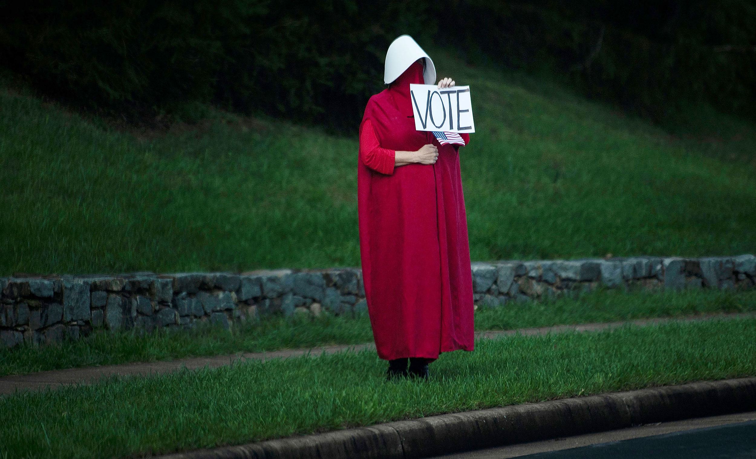 A woman wearing a "Handmaid's Tale" costume stands outside the Trump National Golf Club as President Donald Trump arrives on September 27 in Sterling, Virginia.