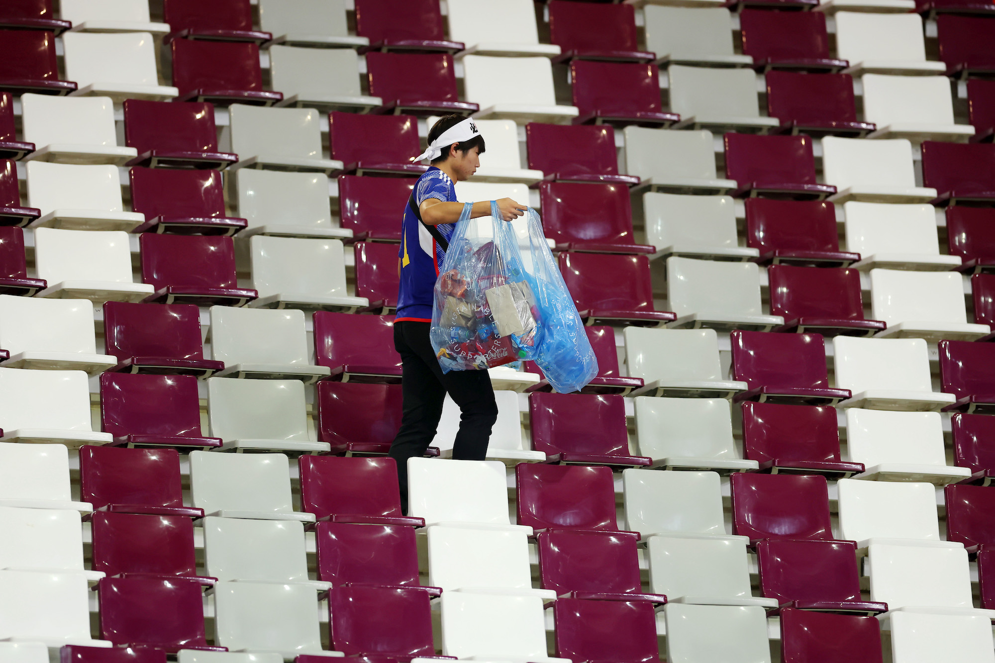 A Japanese fan clears rubbish from the stands during after a match against Germany at Khalifa International Stadium on Wednesday.
